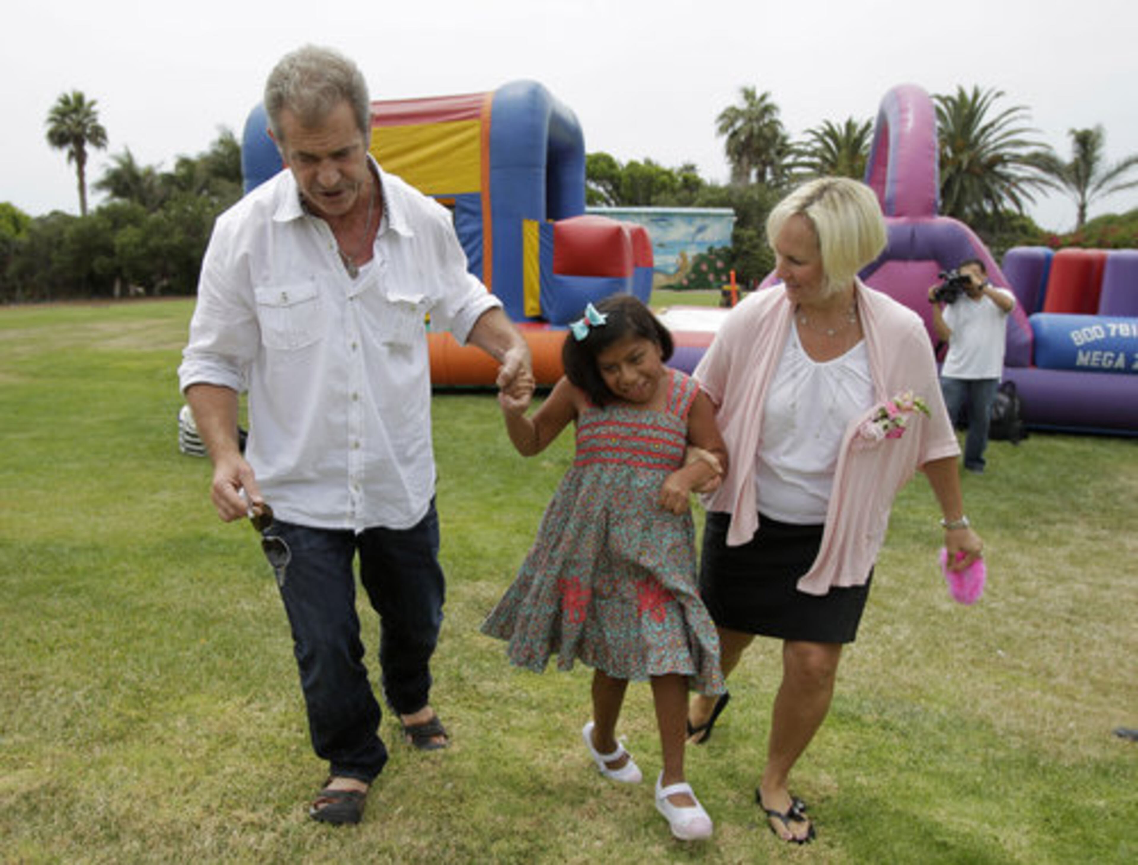 Actor Mel Gibson walks with Josie Hull, center, and Josie's legal guardian Jenny Hull at a birthday party for Josie Hull and her twin sister, Teresita Cajas, in Malibu.
