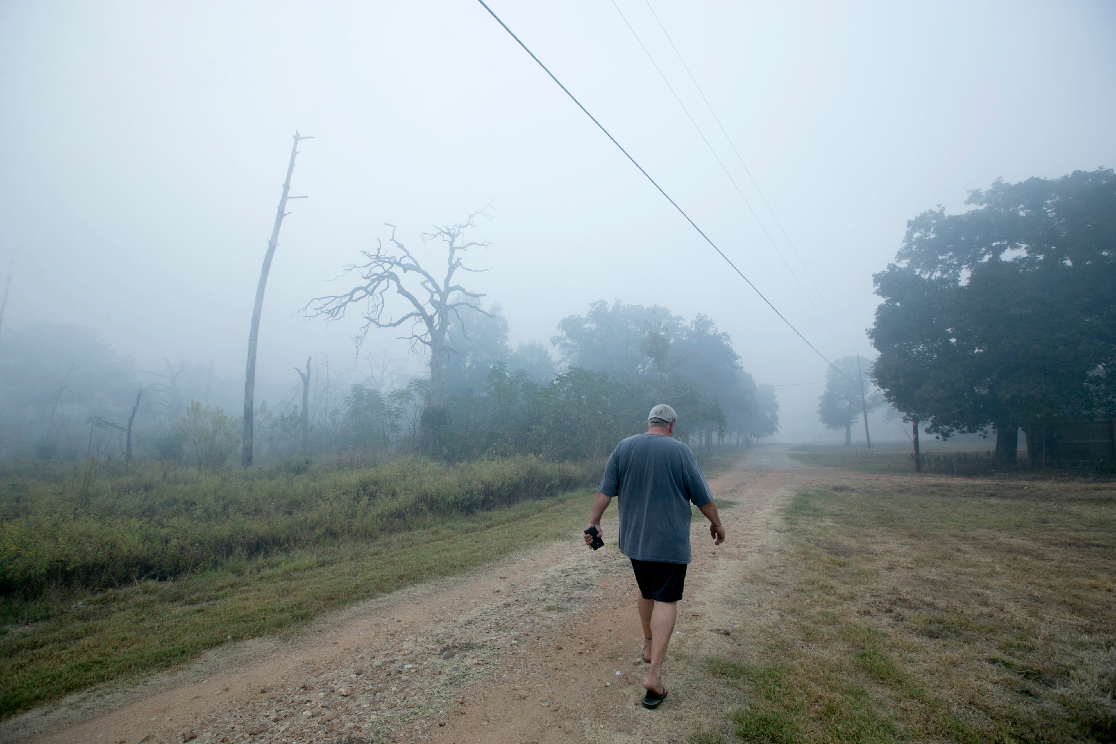 David Dougan walks in thick smioke along Alum Creek East near his home while waiting to make a decision about evacuating from the Hidden Pines Fire on Thursday October 15, 2015. JAY JANNER / AMERICAN-STATESMAN