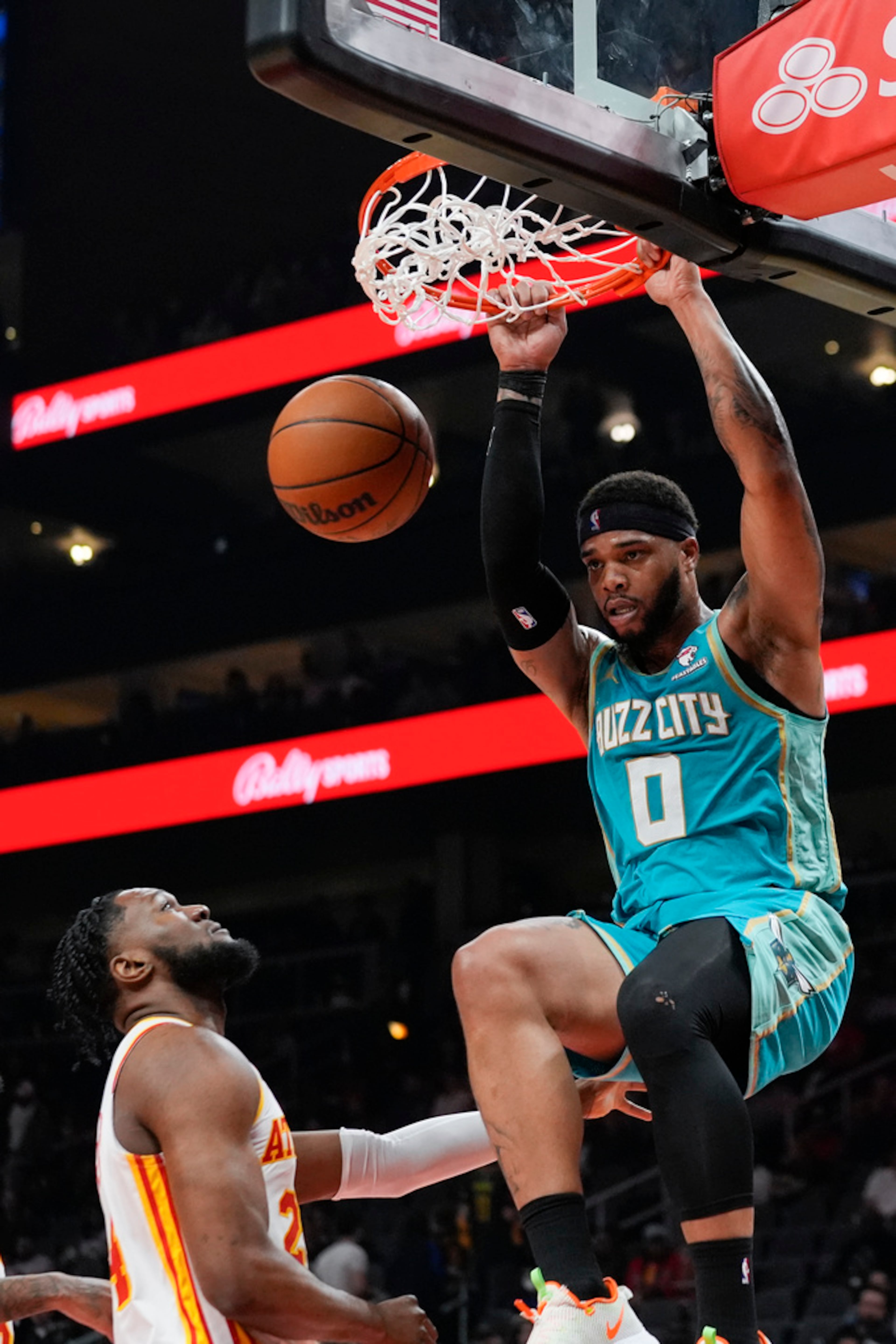 Charlotte Hornets forward Miles Bridges (0) scores as Atlanta Hawks forward Bruno Fernando (24) looks on during the first half of an NBA basketball Saturday, March 23, 2024, in Atlanta. (AP Photo/John Bazemore) bf