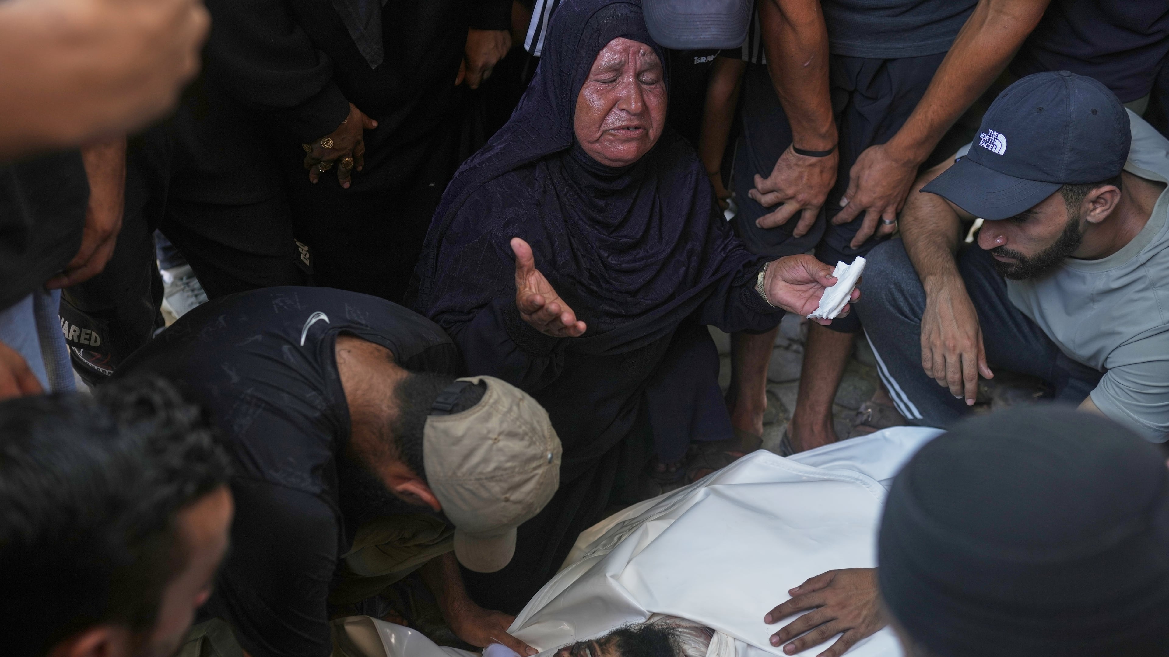 Relatives and friends grieve over the body of Hassan Qahman at a hospital morgue after he was killed in an Israeli airstrike in Gaza City, Saturday, Aug. 1, 2026. (AP Photo/Jehad Alshrafi)