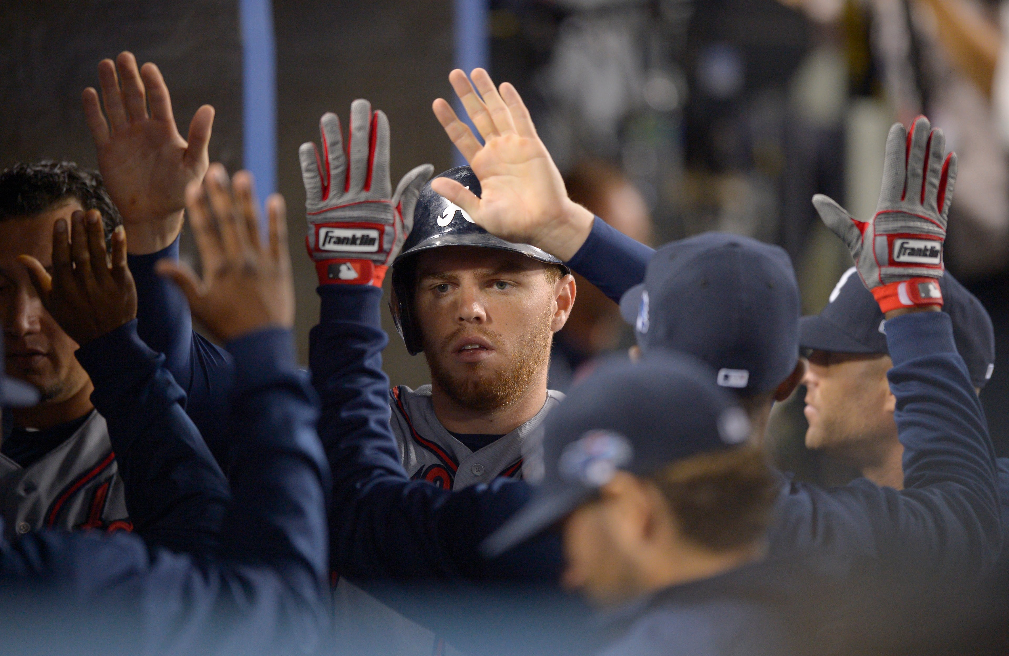 Atlanta Braves' Freddie Freeman is greeted in the dugout after he scored on a single by Chris Johnson in the fourth inning against the Los Angeles Dodgers in Game 4 in the National League baseball division series Monday, Oct. 7, 2013, in Los Angeles. (AP Photo/Mark J. Terrill)