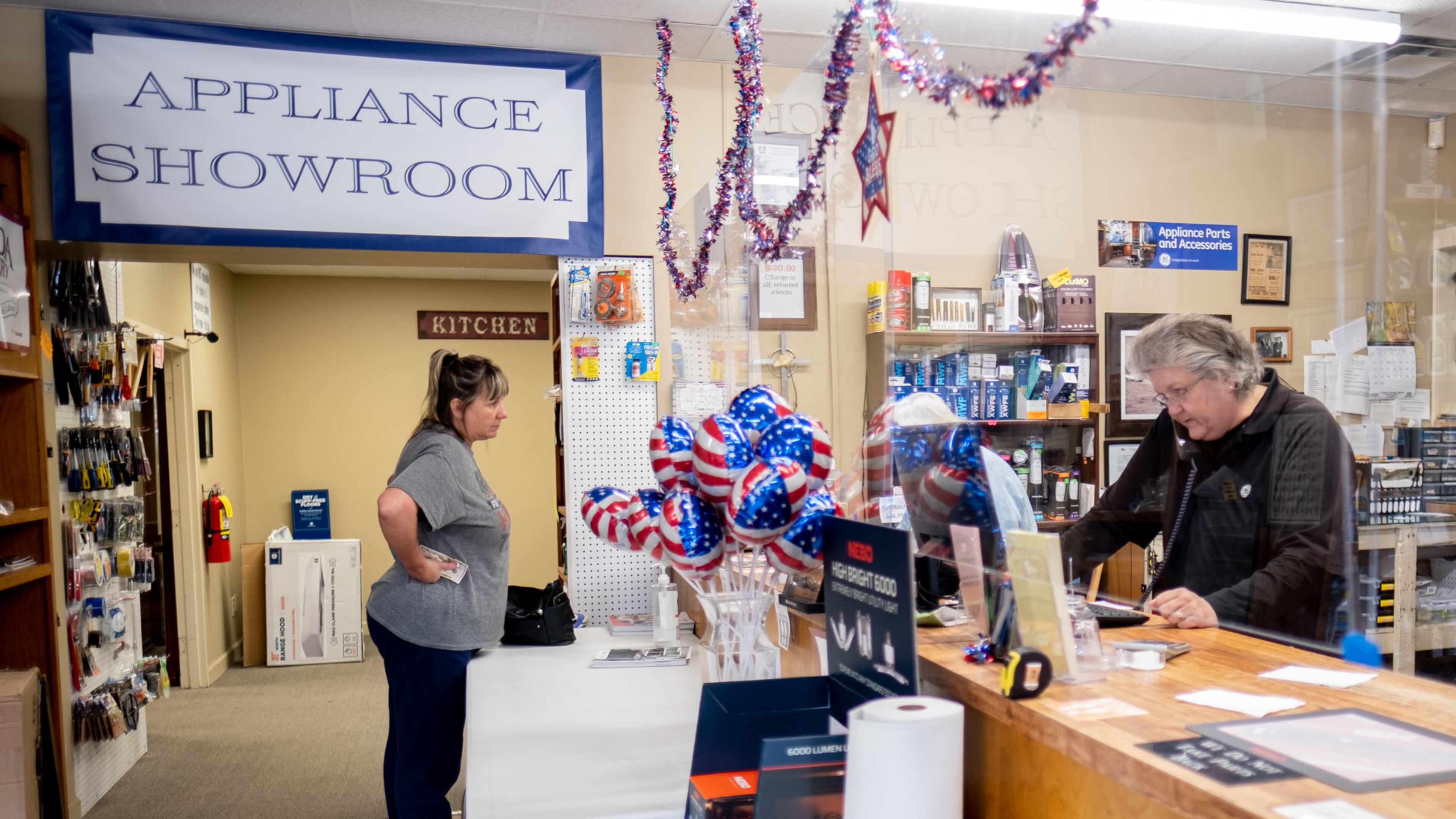 Vickie Mitchell, right, co-owner of Mitchell Appliance Company in Douglasville, talks to a customer on the phone as longtime customer Lori Brangan waits for a part to repair her dryer Thursday afternoon, Nov. 5, 2020. Mitchell said she is having a hard time getting appliances because the pandemic has slowed manufacturing. She also said that parts sales are up because people are repairing their current appliances more due to the shortage. Ben Gray / For the AJC