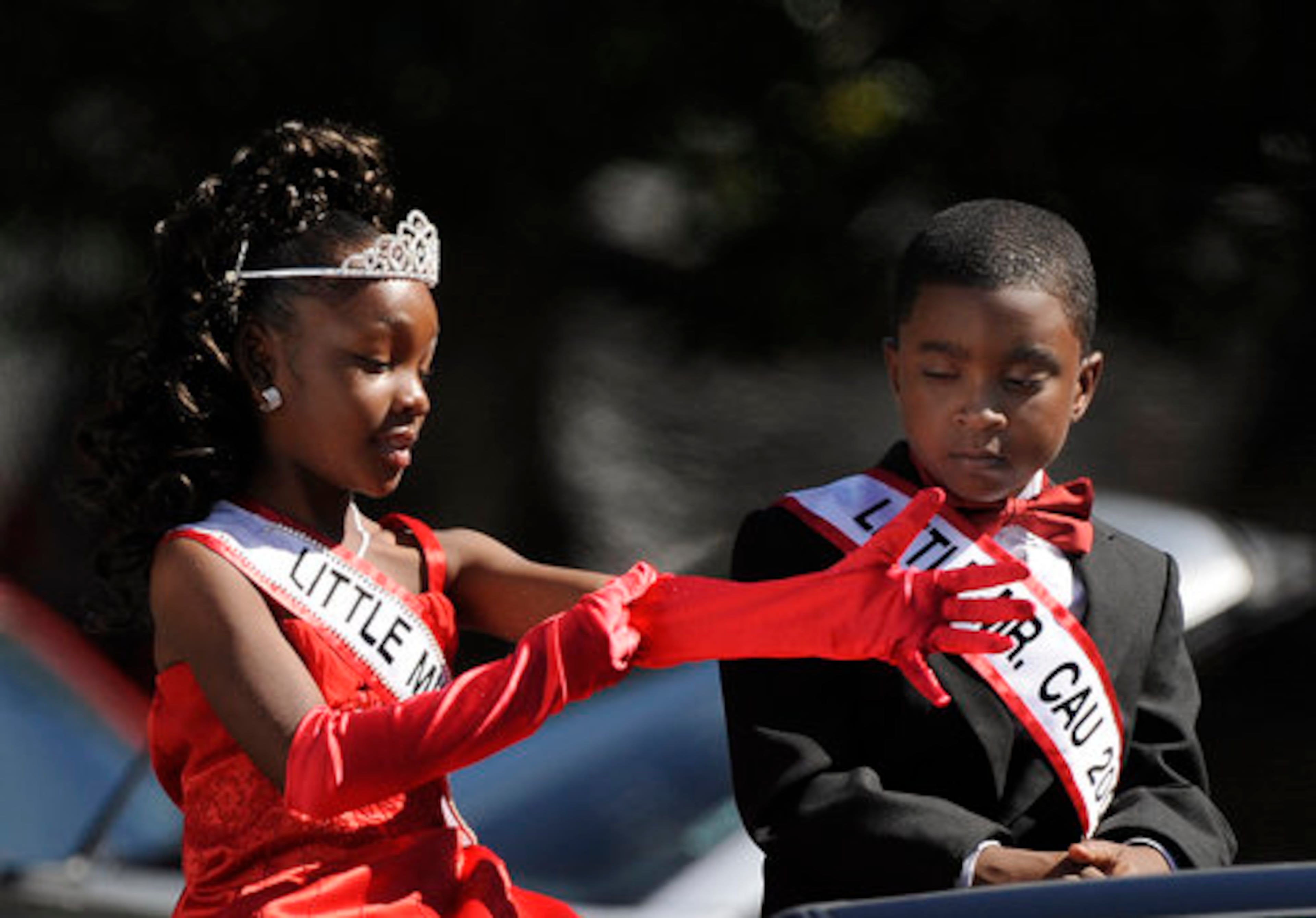 Little Miss Clark Atlanta, seven-year-old Miracle Strozier, puts on her red gloves as seven-year-old Reginald Warren, Little Mr. CAU, watches during Saturday's activities.