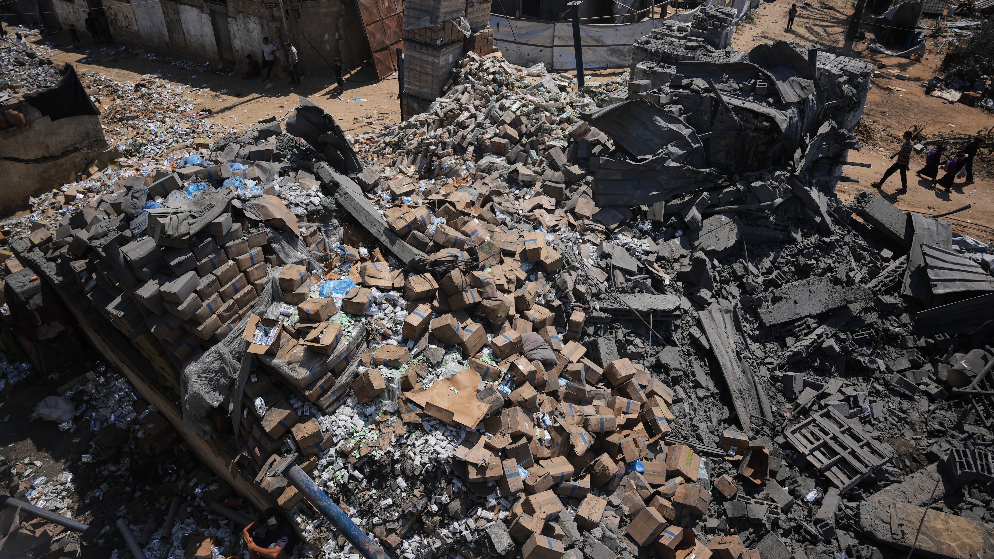 Palestinians walk past a food-aid warehouse damaged in an Israeli airstrike that targeted a nearby house in Deir al-Balah, central Gaza Strip, Wednesday, Aug. 26, 2026. (AP Photo/Abdel Kareem Hana)