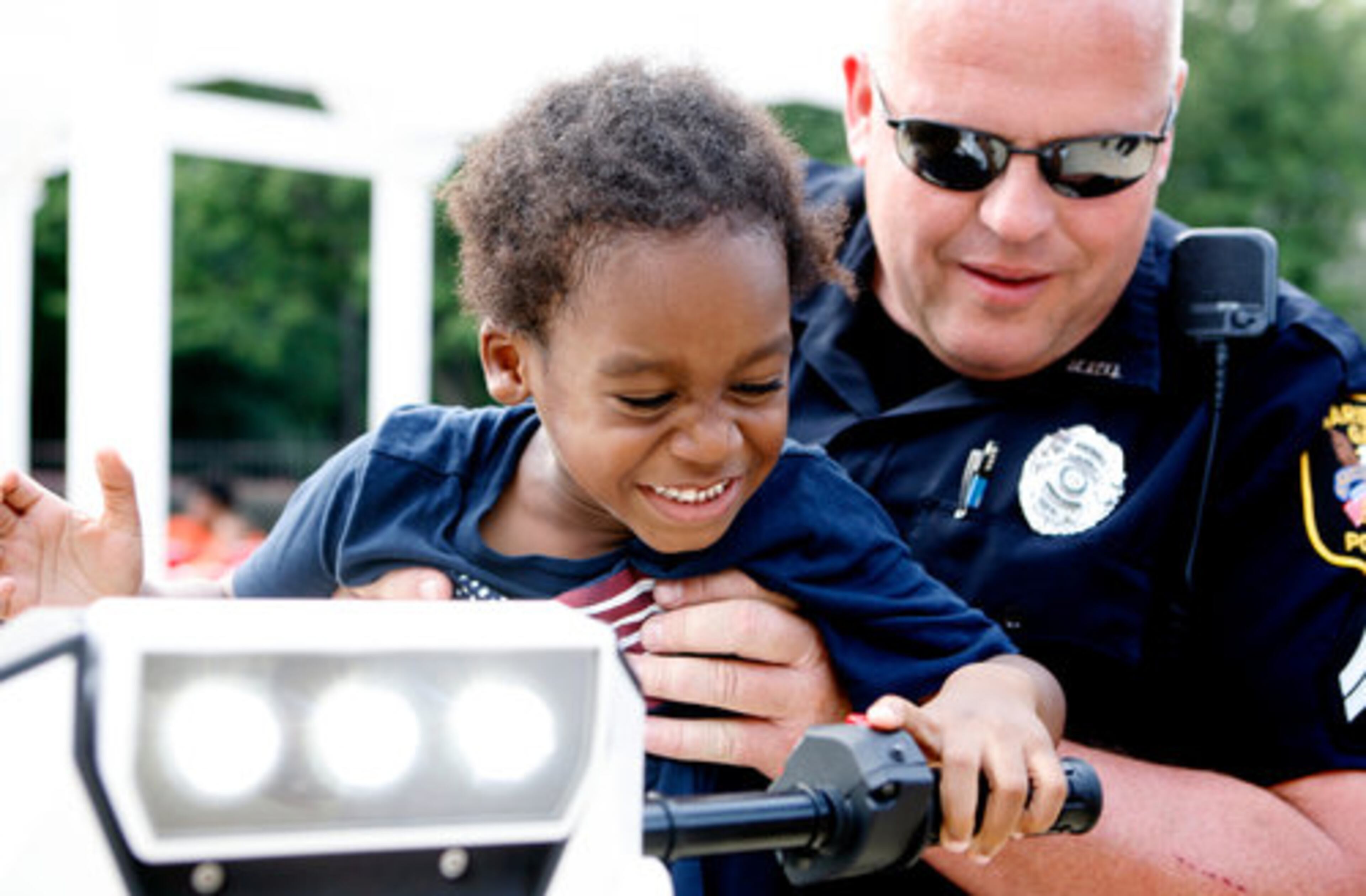 Marietta Police Officer Don Smith holds up 4-year-old Romeo Coleman so he can activate the siren on the police department's T3 Series electric standup vehicle during National Night Out at the Notting Hills apartment complex on Tuesday, Aug. 3, 2010.