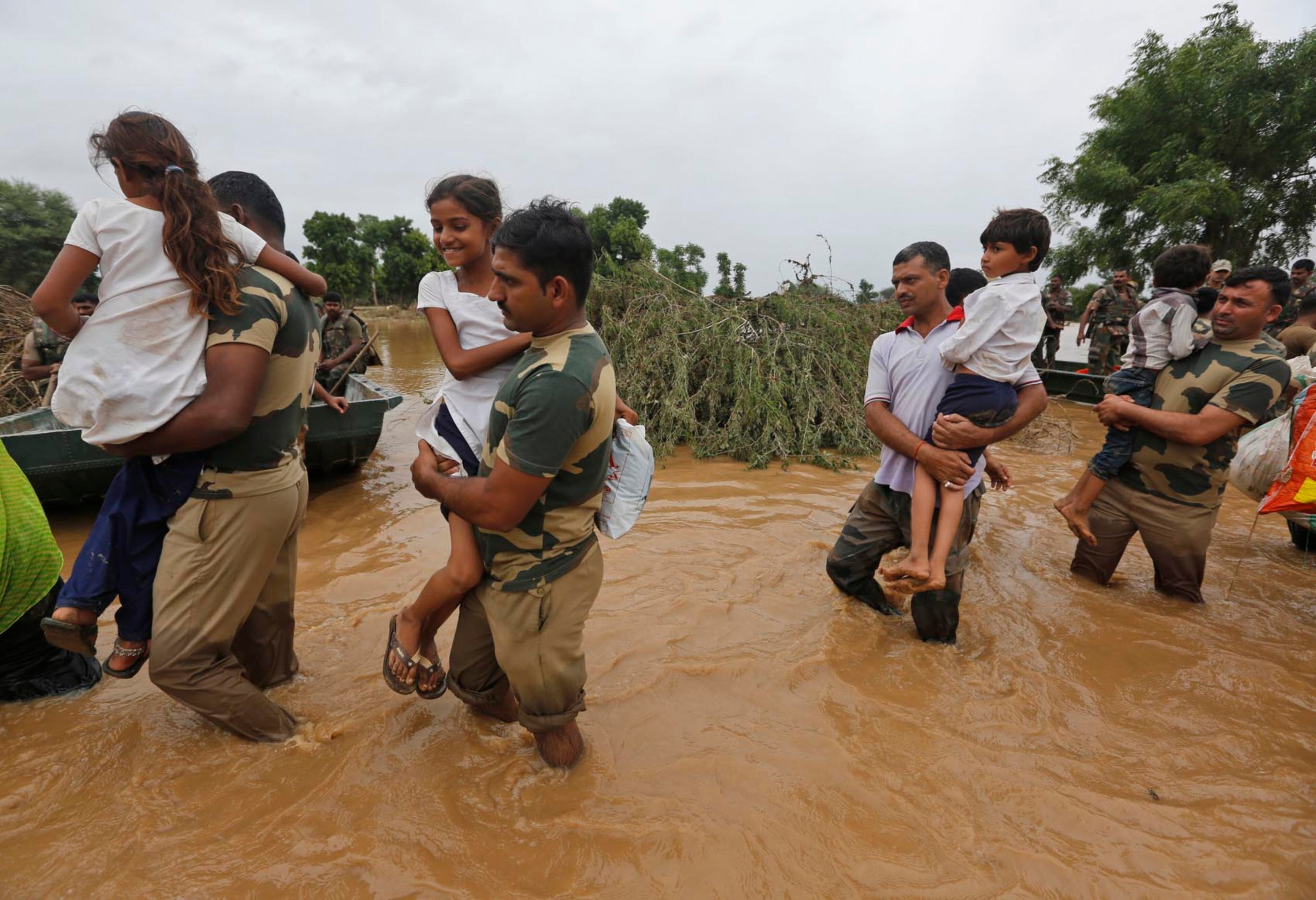 India army soldiers carry children rescued from flood affected villages near Thara in Banaskantha district, Gujarat, India, Wednesday, July 26, 2017. At least 29 people have died in the state of Gujarat amid torrential rains. This week's deaths have taken the toll the state to 83 since the start of the monsoon season which runs from June through September. (AP Photo/Ajit Solanki)