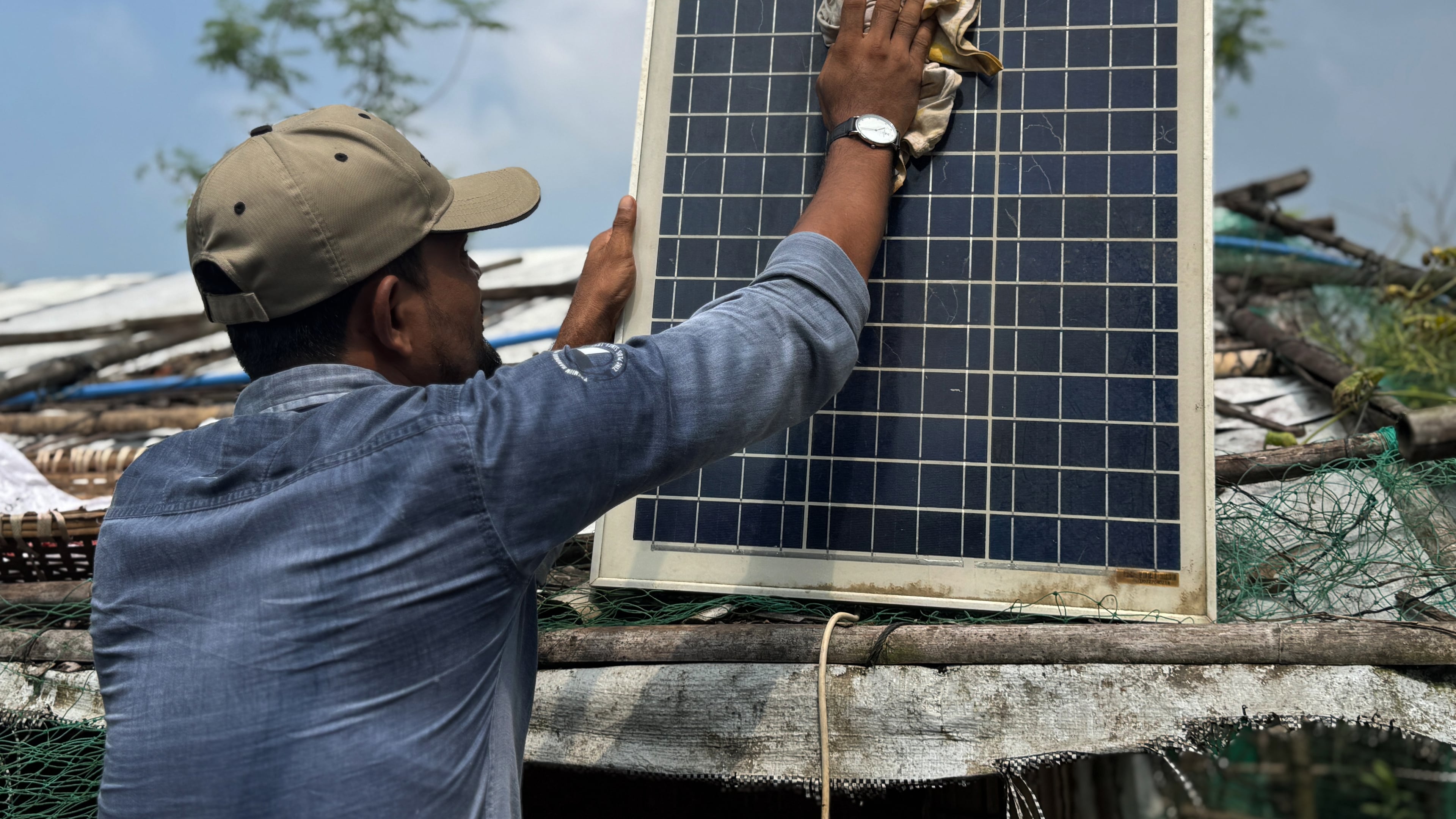 In this photo taken with a phone, Mohammed Saber cleans a solar panel to ensure it charges properly on Oct. 4, 2026, in Teknaf, Bangaldesh. (AP Photo/Abdul Khan Dkl)
