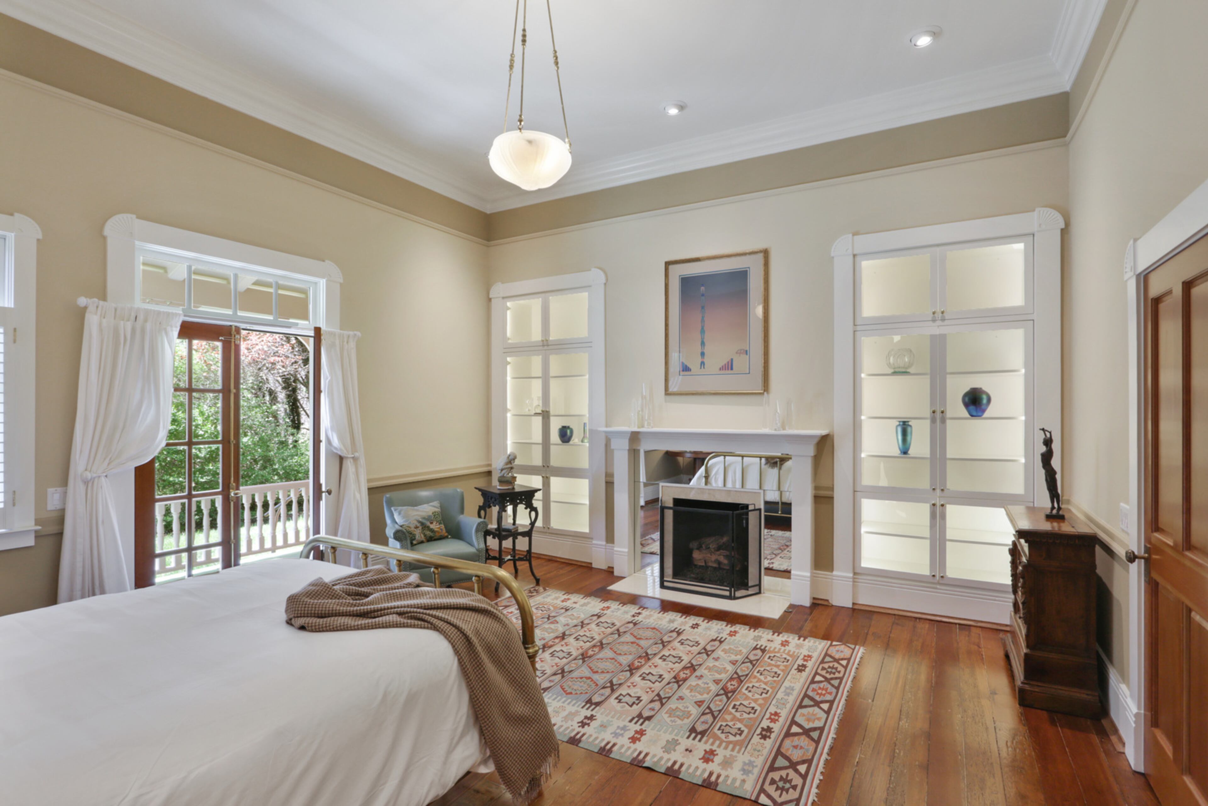 The owner's suite has beautiful wide heart pine boards as well as another original fireplace that has been converted to gas. The doors to the outside lead to the wrap-around side porch. Text by Jill Huitron