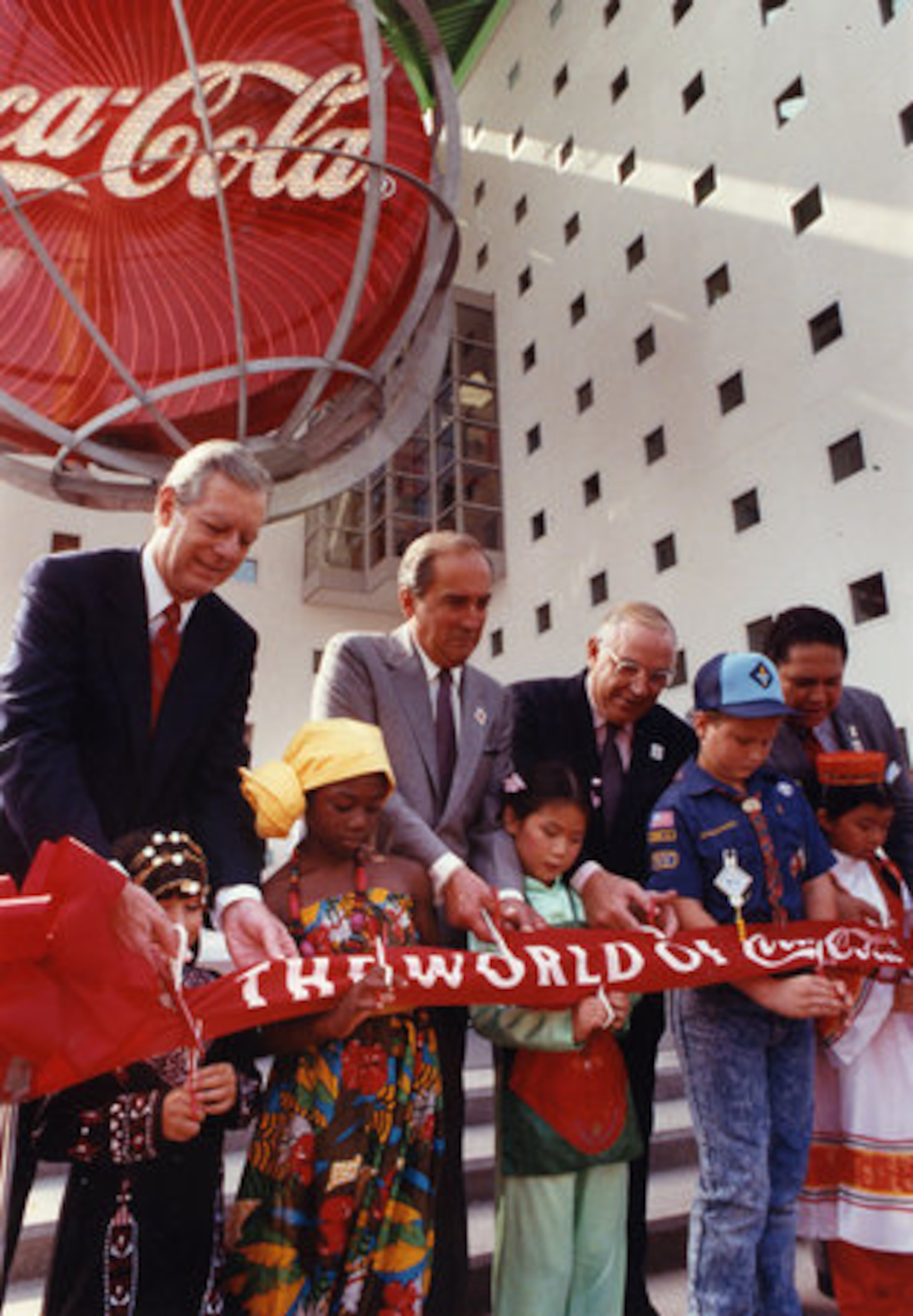 In August 1990, Keough (standing third from left) joined children and (from left) Gov. Joe Frank Harris, Coca-Cola Chairman Roberto Goizueta and Mayor Maynard Jackson in cutting the ribbon for the Coca-Cola Pavilion at Underground Atlanta.