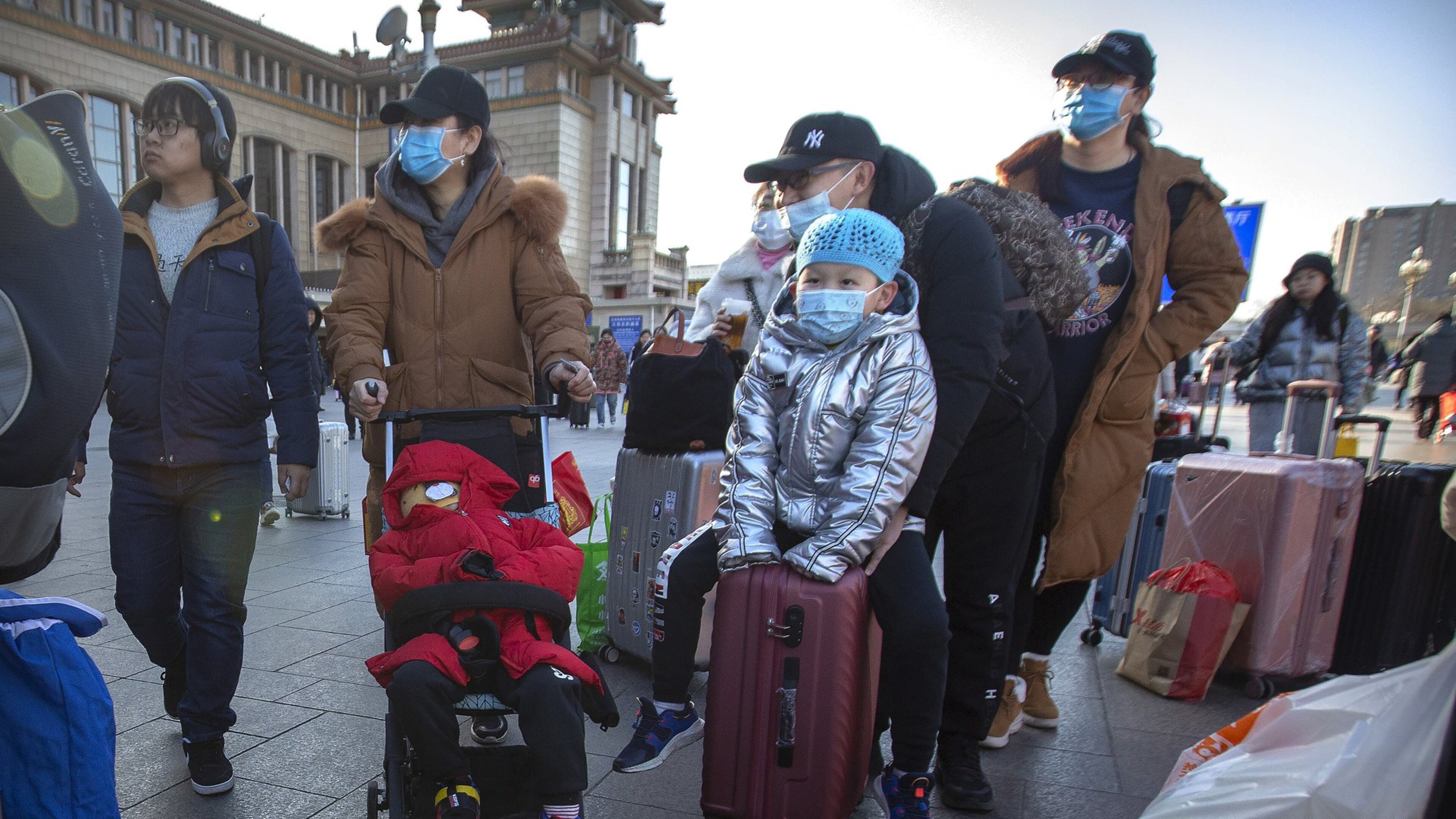 Travelers wear face masks as they walk outside of the Beijing Railway Station in Beijing, Monday, Jan. 20, 2020. China reported Monday a sharp rise in the number of people infected with a new coronavirus, including the first cases in the capital. The outbreak coincides with the country’s busiest travel period, as millions board trains and planes for the Lunar New Year holidays. (AP Photo/Mark Schiefelbein)