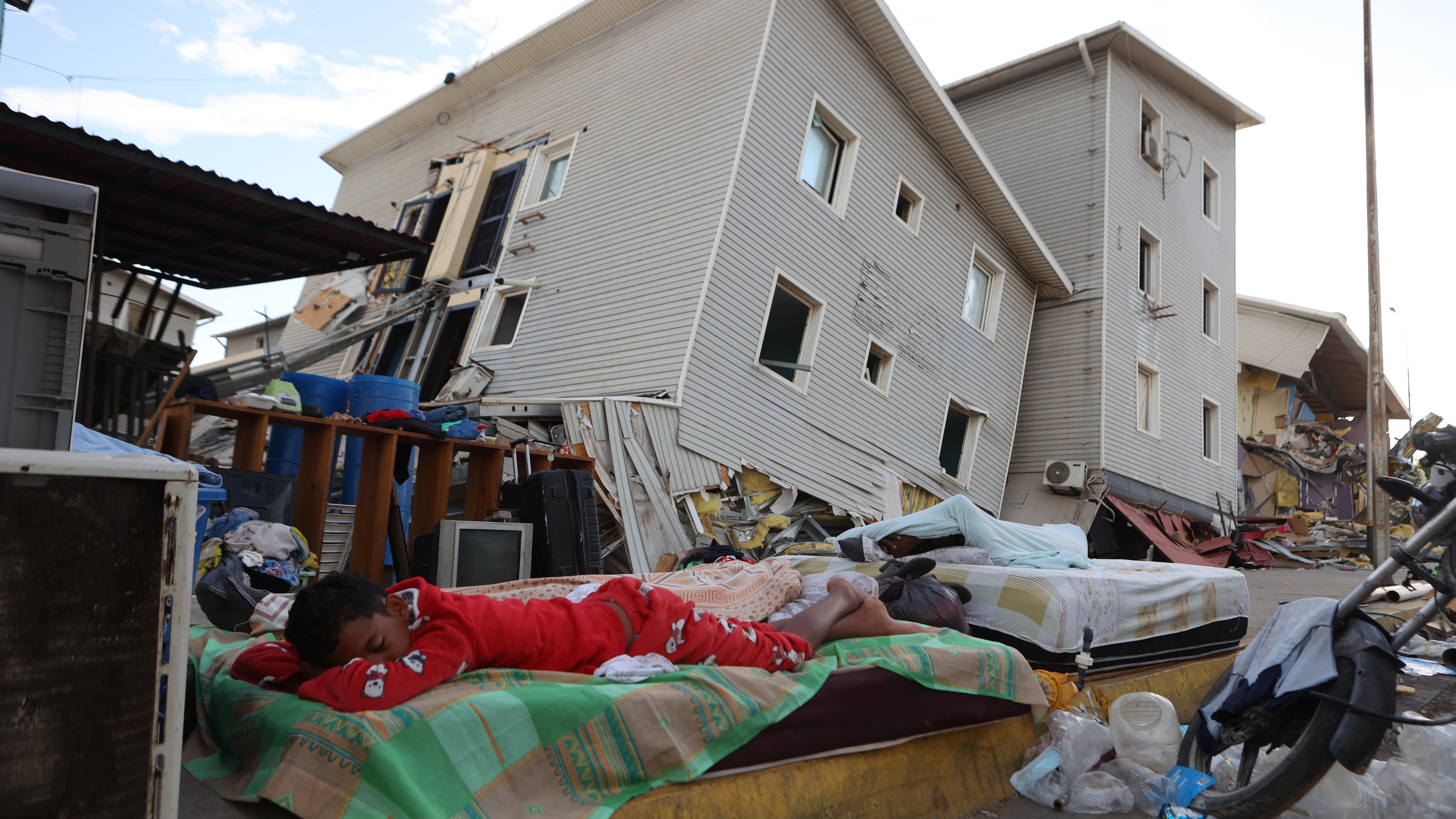A boy sleeps outside earthquake-damaged homes in Catia La Mar, Venezuela, Sunday, June 28, 2026. (AP Photo/Pedro Mattey)