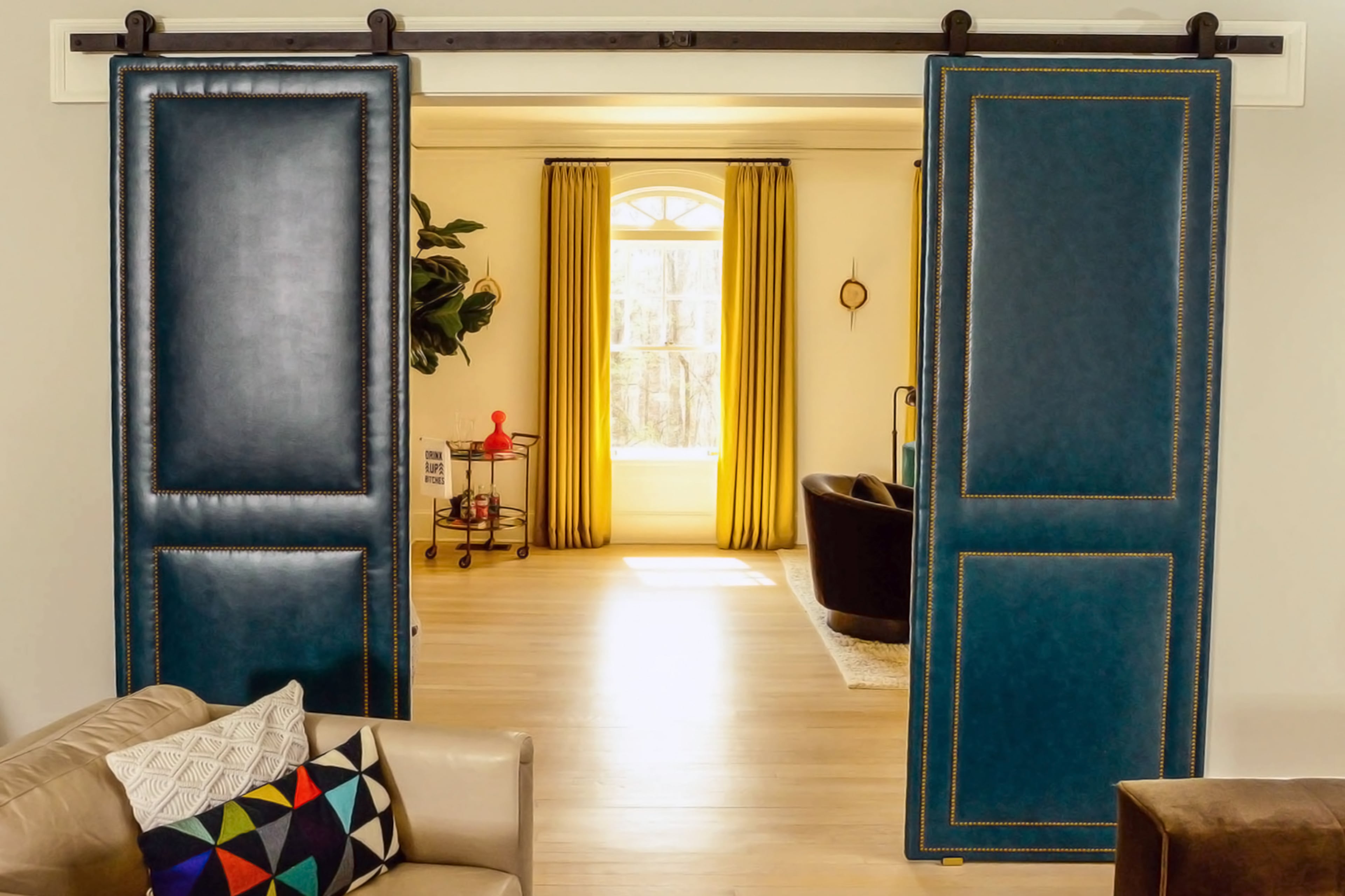 Blue faux leather barn doors with gold nailhead trim separate the living space from the sitting room in Atlanta's Druid Hills neighborhood.