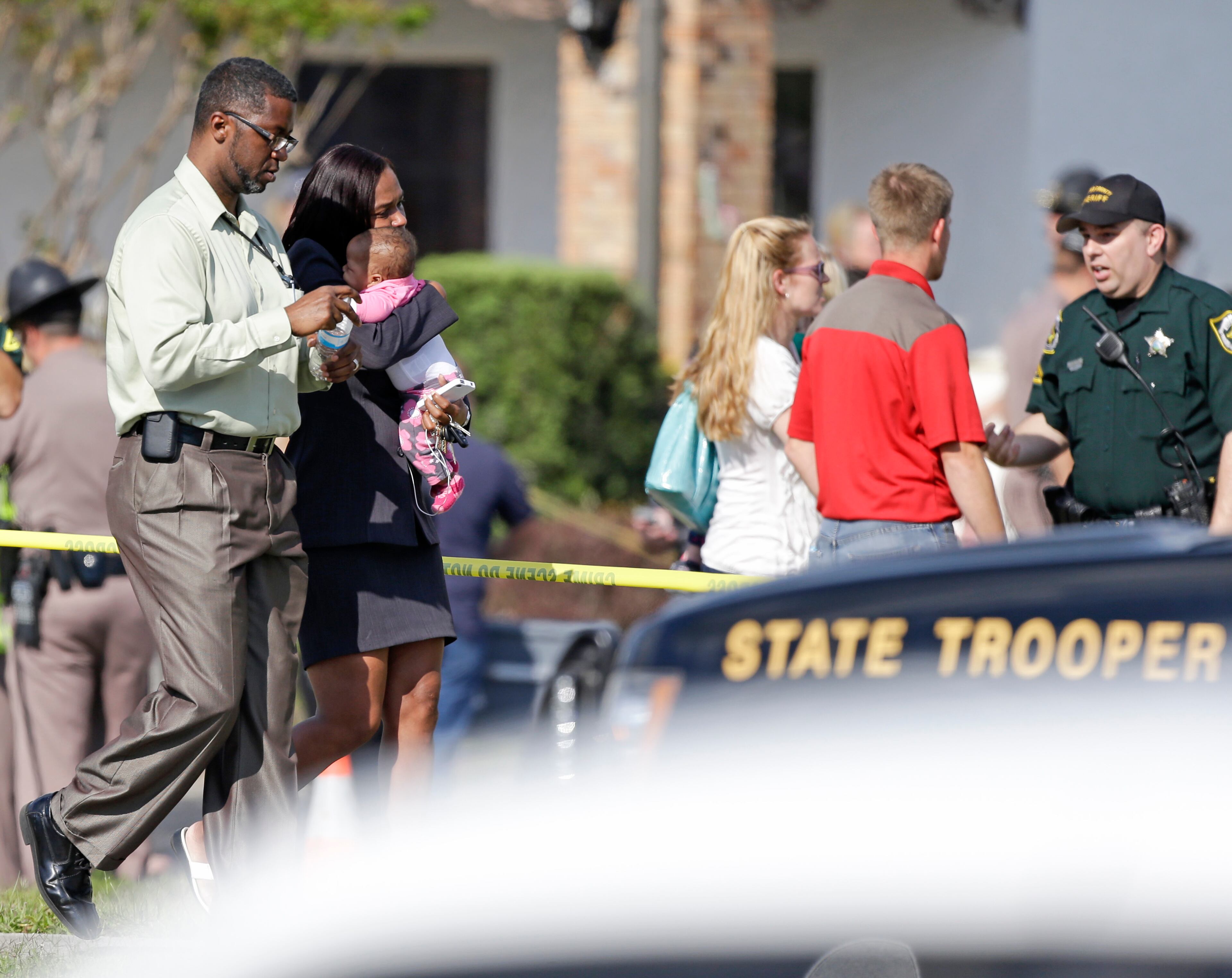 Parents leave a day care center with their children after a vehicle crashed into the center, Wednesday, April 9, 2014, in Winter Park, Fla. (AP Photo/John Raoux)