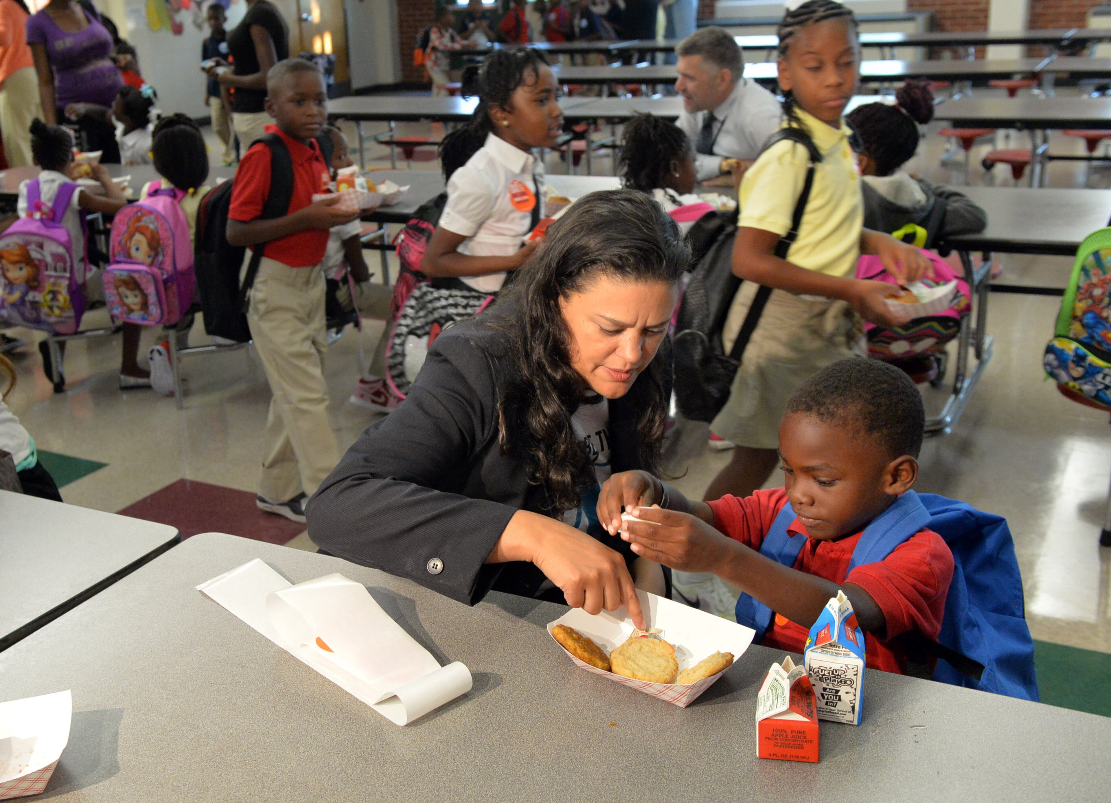 Kindergartner Luke Duncan, 5, gets help with his breakfast from Dr Carstarphen. Students start back to school at Bethune Elementary School in Atlanta on the first day of classes, Monday August 4, 2014. APS Superintendent Meria Carstarphen greeted students, parents, faculty and staff during the morning. KENT D. JOHNSON/KDJOHNSON@AJC.COM