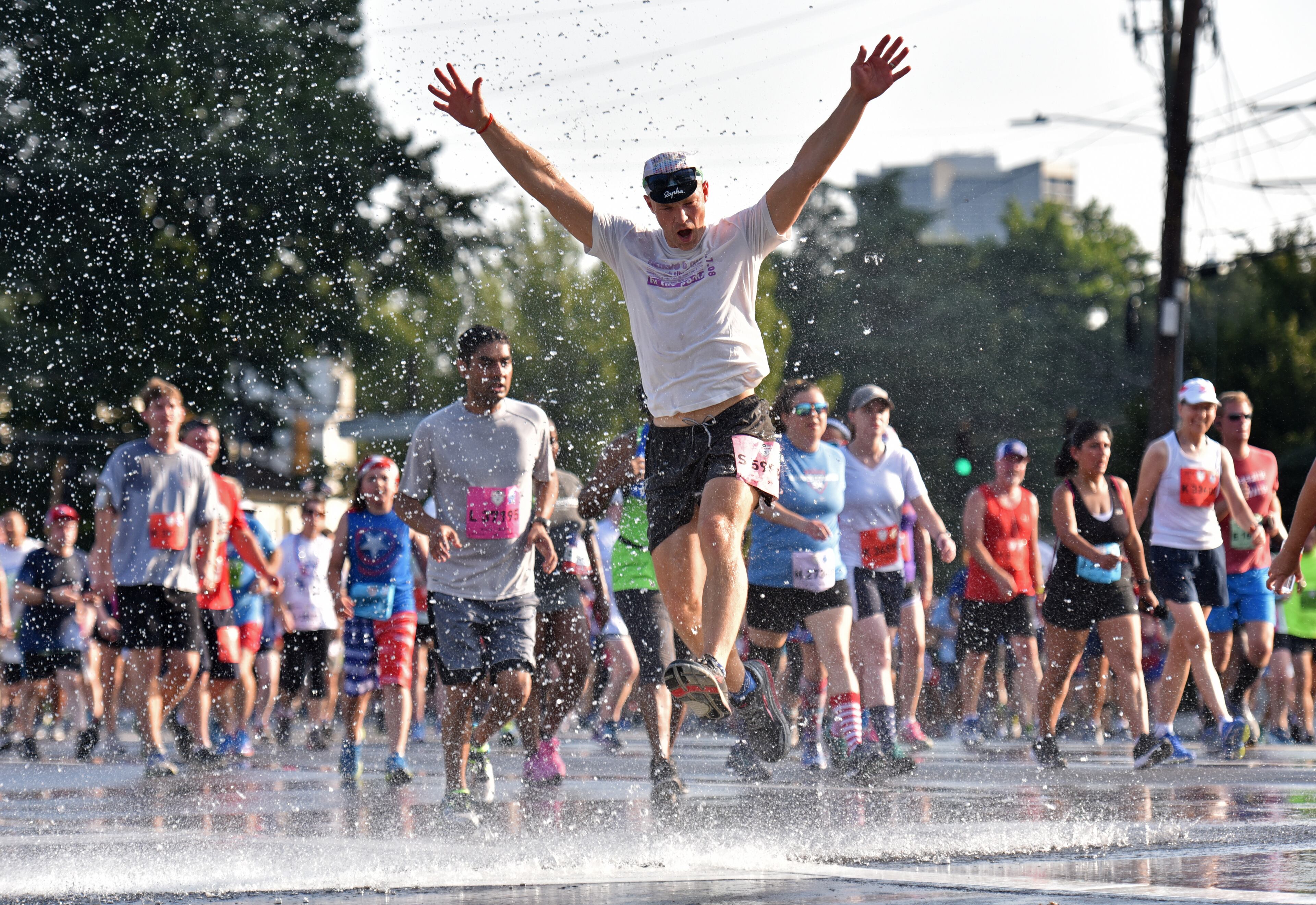 July 4, 2018 Atlanta - Runners cool off in a shower of water that refreshed them just before they approach Cardiac Hill during the AJC Peachtree Road Race on Wednesday, July 4, 2018. HYOSUB SHIN / HSHIN@AJC.COM