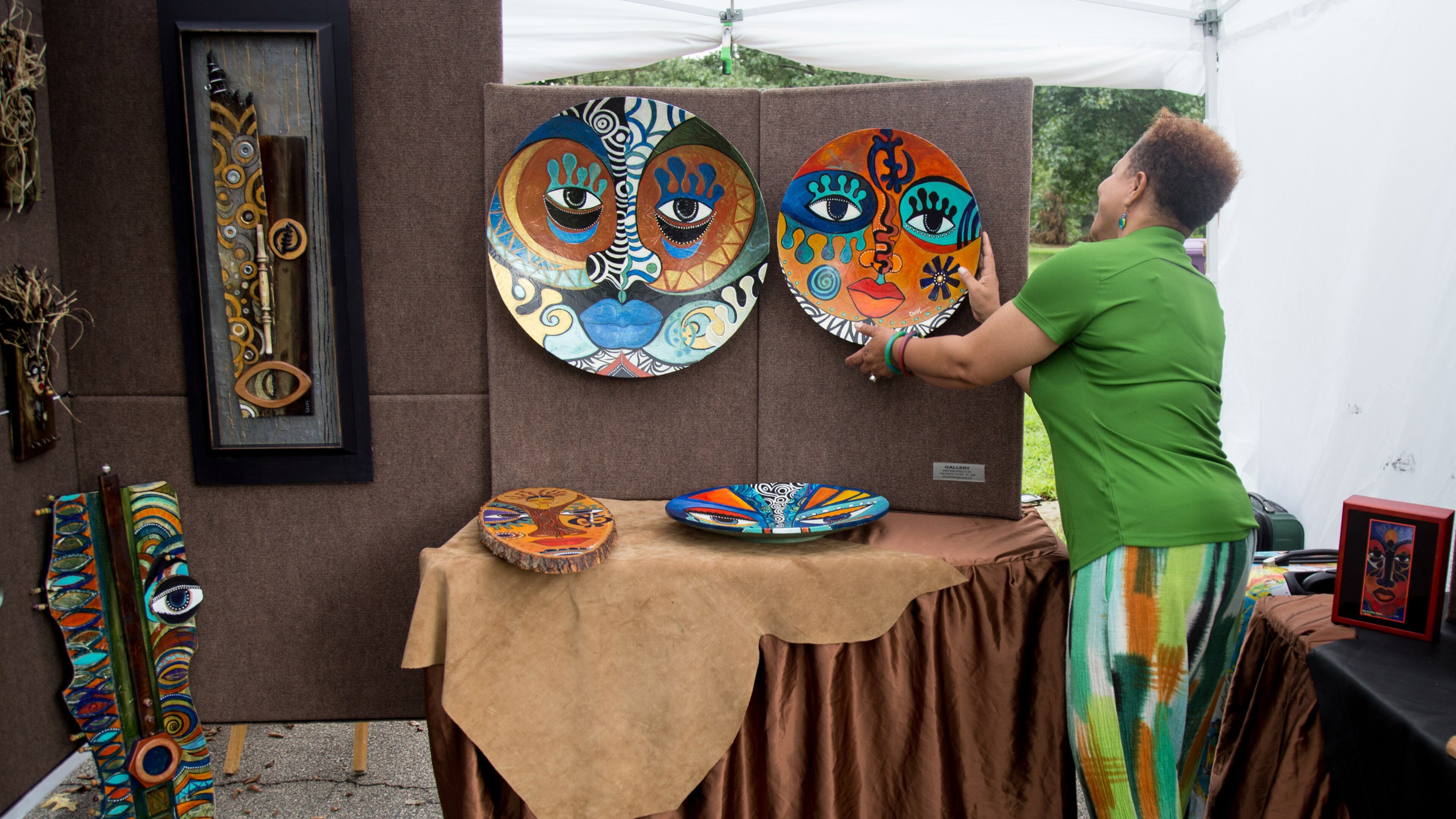 Artist Sylvia Cohen adjusts one of her paintings during the ninth annual Piedmont Park Arts Festival on Saturday, August 18, 2018. STEVE SCHAEFER / SPECIAL TO THE AJC
