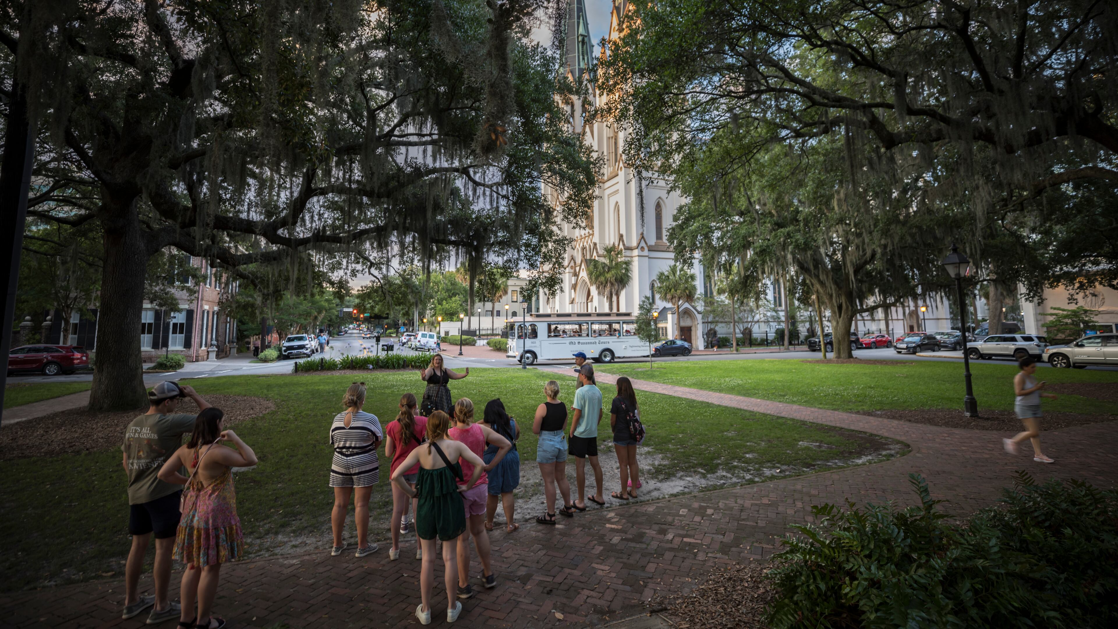 SAVANNAH, GA - MAY 28, 2024: A tour guide starts a walking tour at Lafayette Square with the historic Cathedral Basilica of St. John the Baptist as a backdrop, Tuesday, May 28, 2024, in Savannah, Ga. With city's tourism surge affecting residents quality of life, elected leaders are exploring limits on trolley, horse carriage and walking tours. (AJC Photo/Stephen B. Morton)