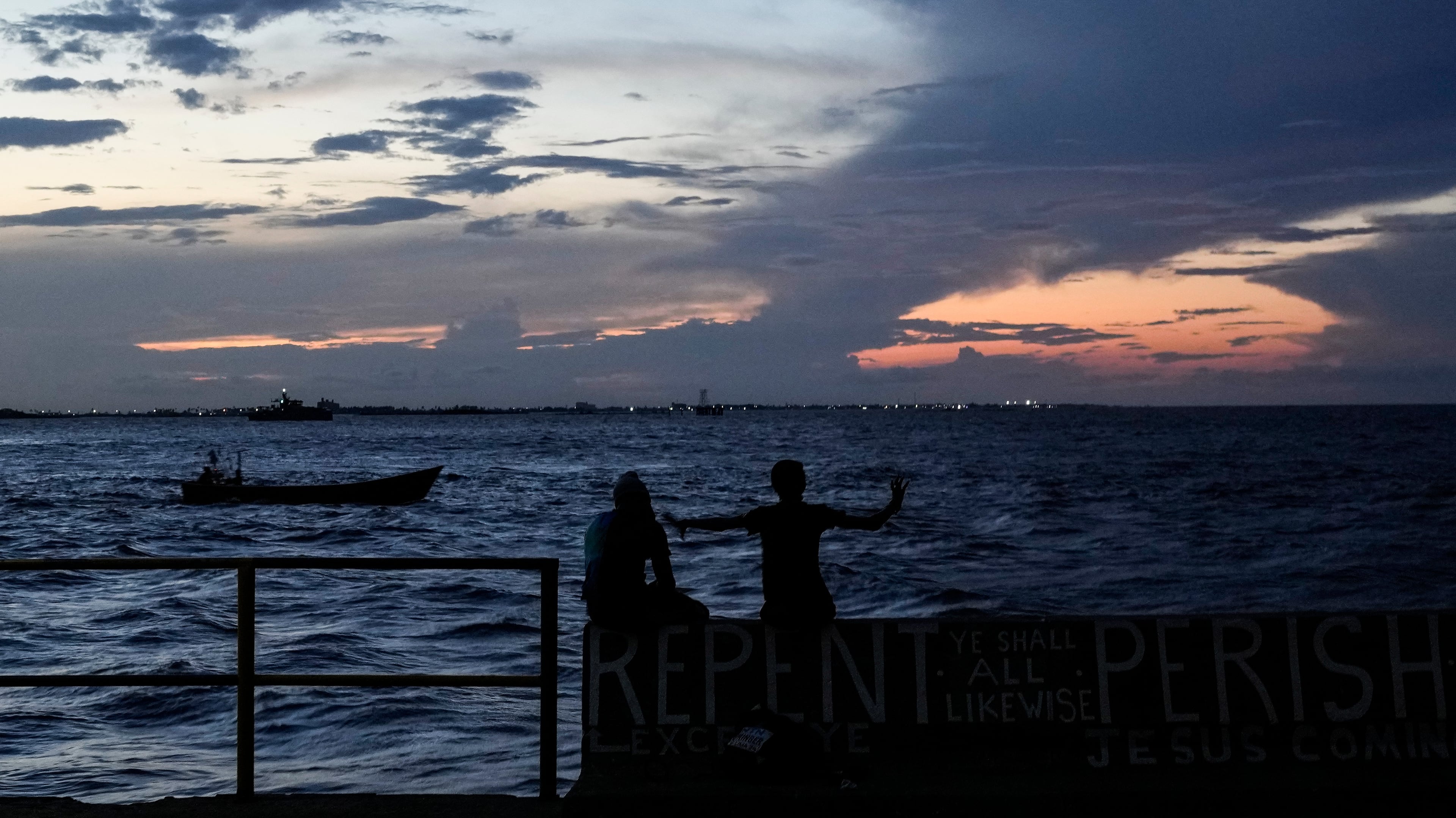 FILE - People sit on the seawall as the sun sets in Georgetown, Guyana, Tuesday, Nov. 19, 2024. (AP Photo/Matias Delacroix, File)