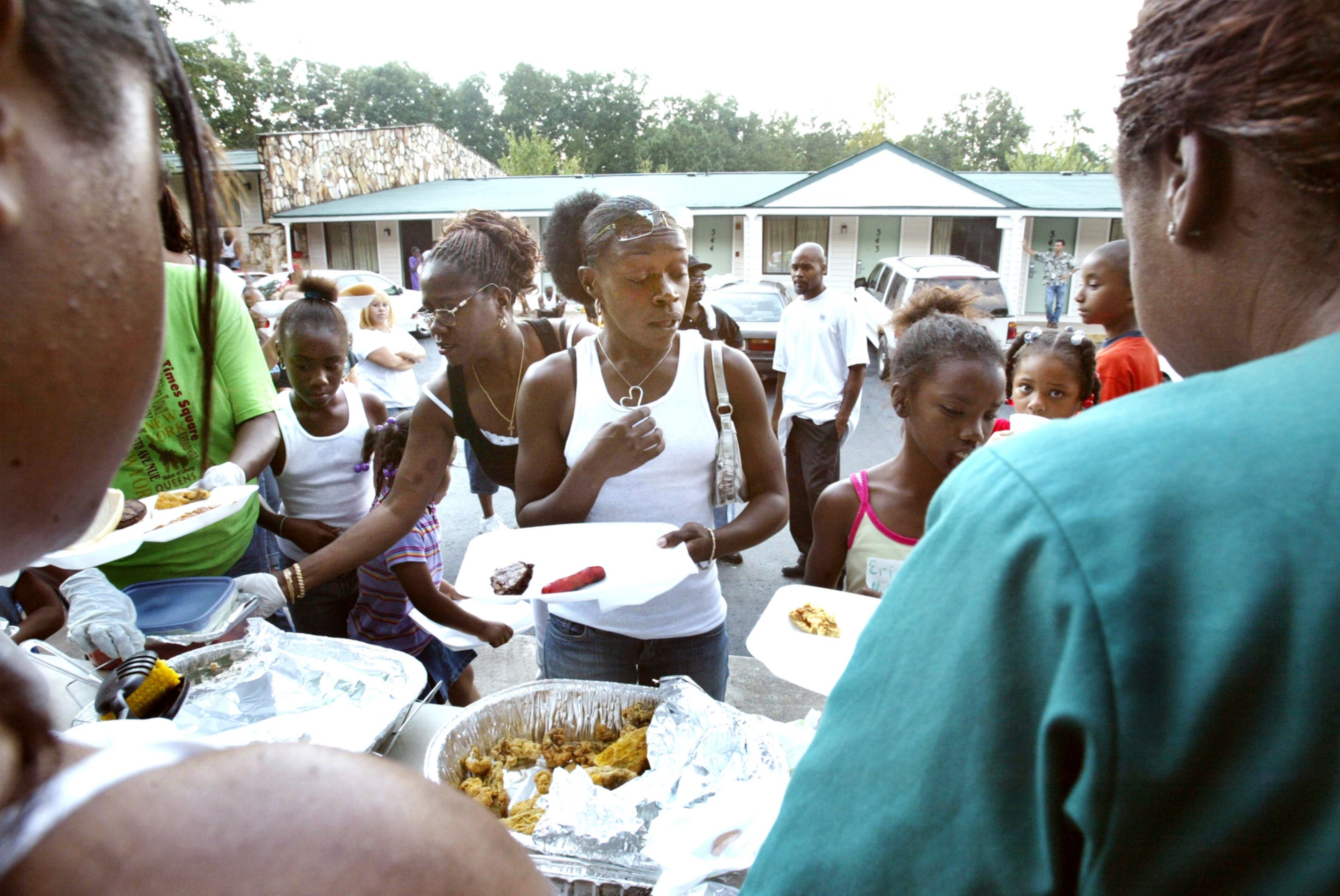 050905 - UNION CITY, GA - Slidell Louisiana evacuees including Faith Allen, center, white tank top, (cq) accept food from the Carroll extended family Monday, Sept. 5, 2005 outside the Motel 6 on Flat Shoals Road in Union City where a large group of Slidell evacuees have been staying for more than a week. Several branches of the Carroll family came to the hotel with hot food and clothing. (JENNI GIRTMAN/STAFF)