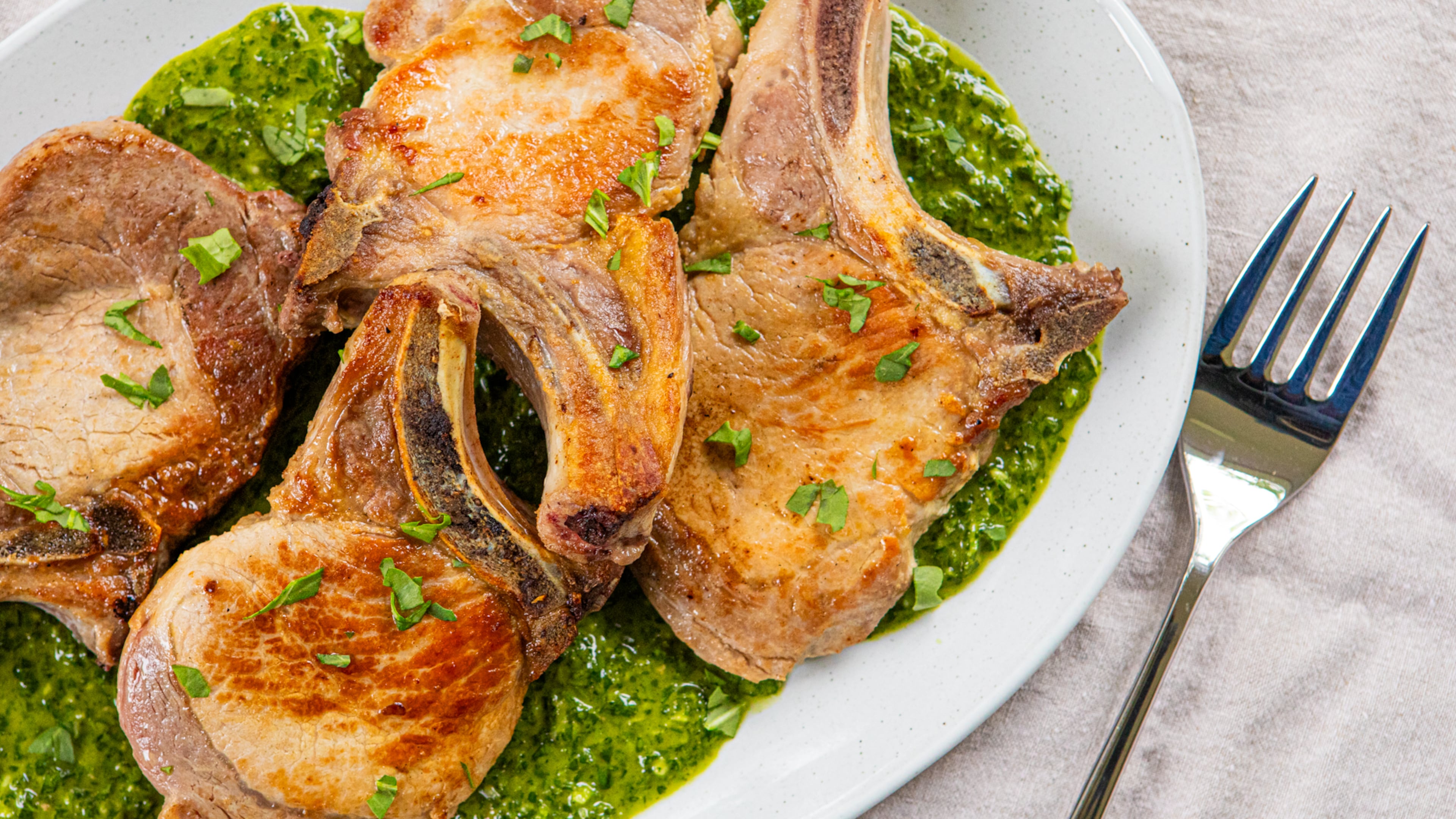 Pan-seared pork chops with salsa verde. (Aaliyah Man for The Atlanta Journal-Constitution)