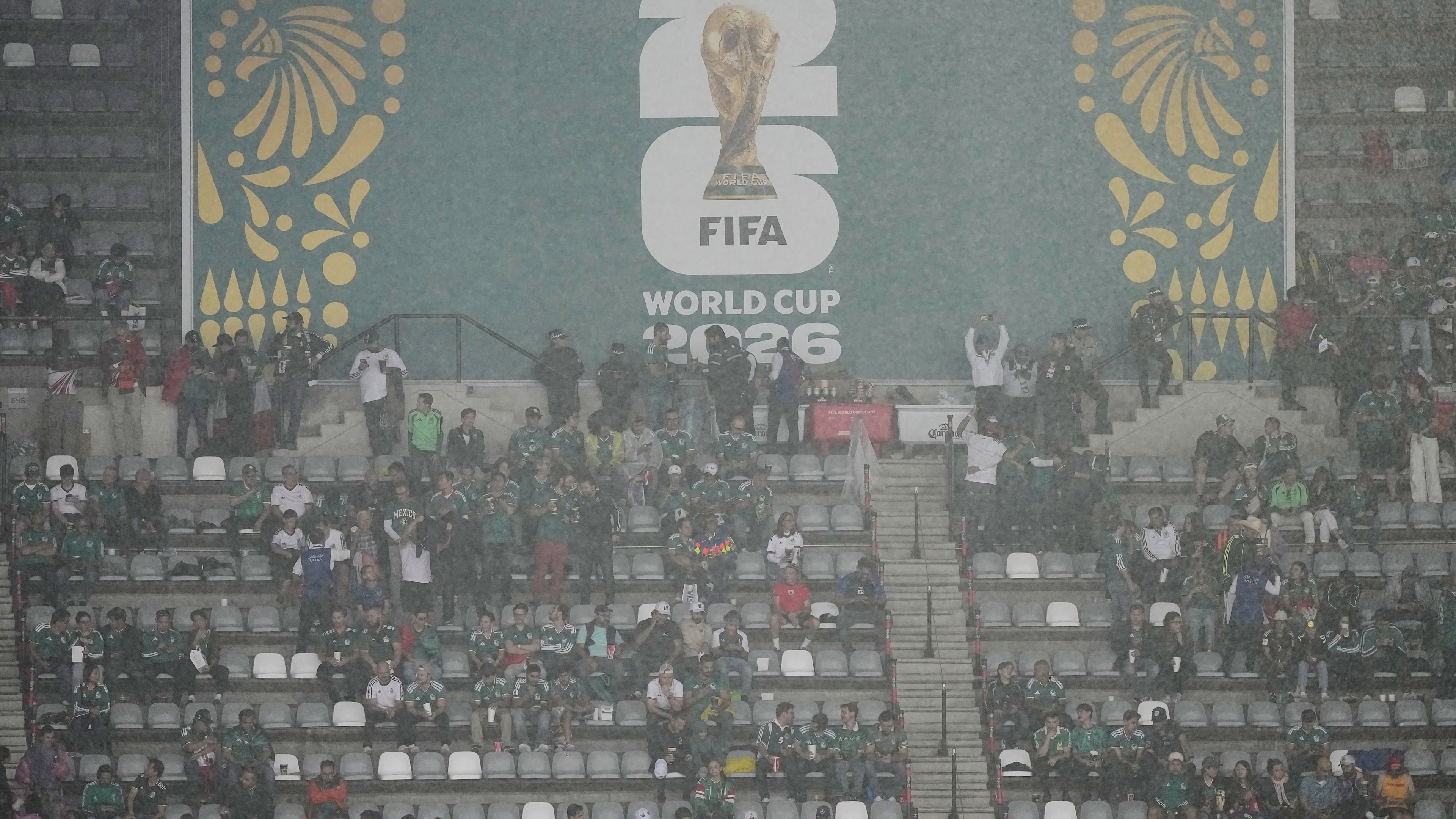 Fans wait out the rain as the game between Mexico and England is delayed due to weather for the World Cup round of 16 soccer match in Mexico City, Sunday, July 5, 2026. (AP Photo/Fernando Llano)