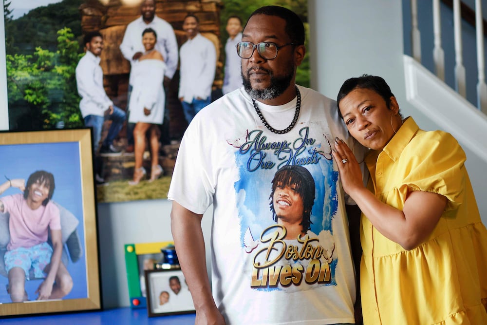 Ramonne and Terrica Thomas of Mableton, surrounded by images of their son, Boston Thomas. They're suing Cobb County to learn more about the events leading to their son's death. (Miguel Martinez/AJC)