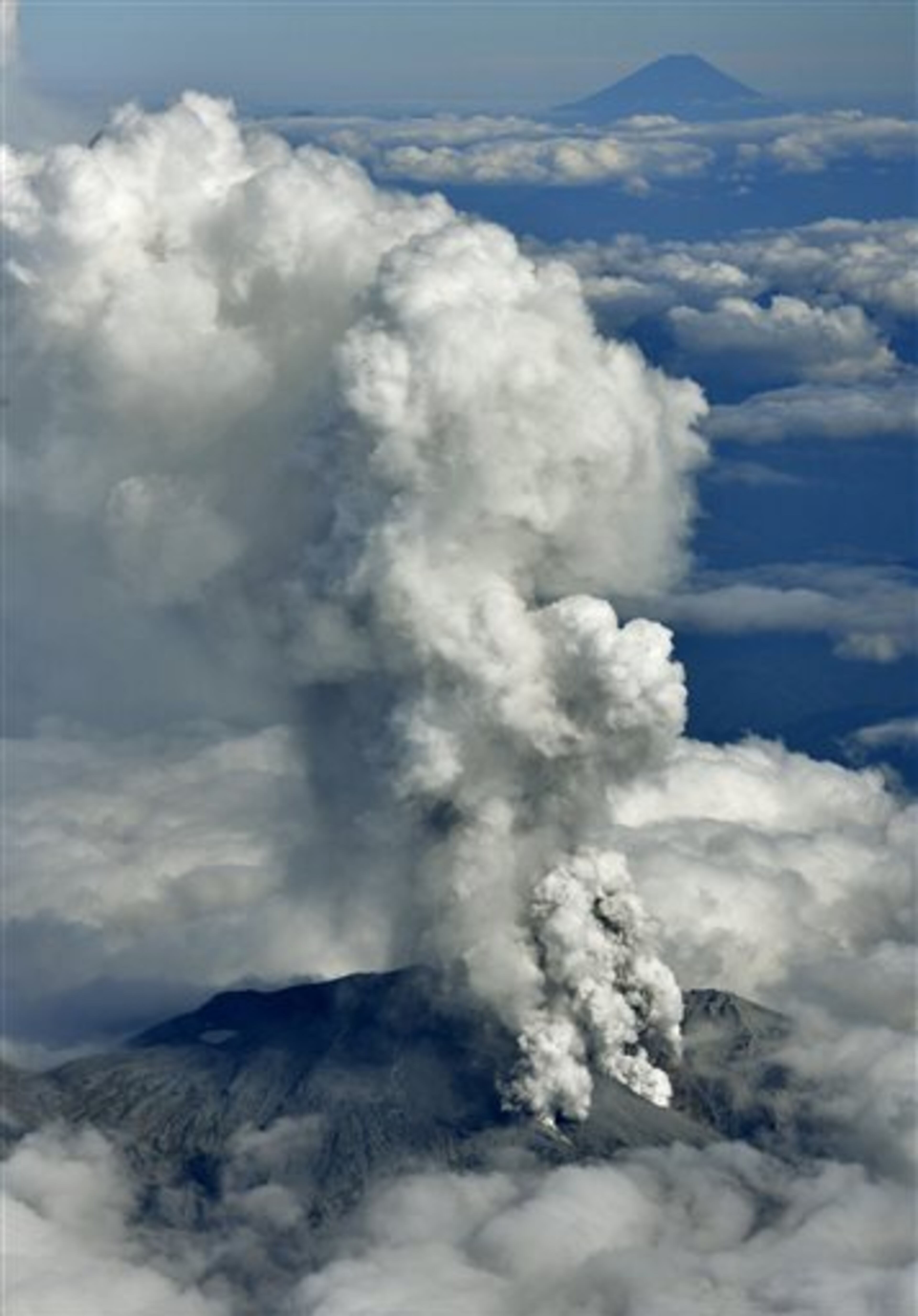 Dense fumes are spewed out from Mt. Ontake as the volcano erupts in central Japan Saturday, Sept. 27, 2014. Mt. Ontake erupted Saturday, sending a large plume of ash high into the sky and prompting a warning to climbers and others to avoid the area. Japanese broadcaster NHK, citing local authorities, said there were reports of injuries, but no word on their severity. It also reported that people had been evacuated from a mountain lodge. Mount Fuji, Japan's tallest mountain, is seen at top right. (AP Photo/Kyodo News) JAPAN OUT, MANDATORY CREDIT