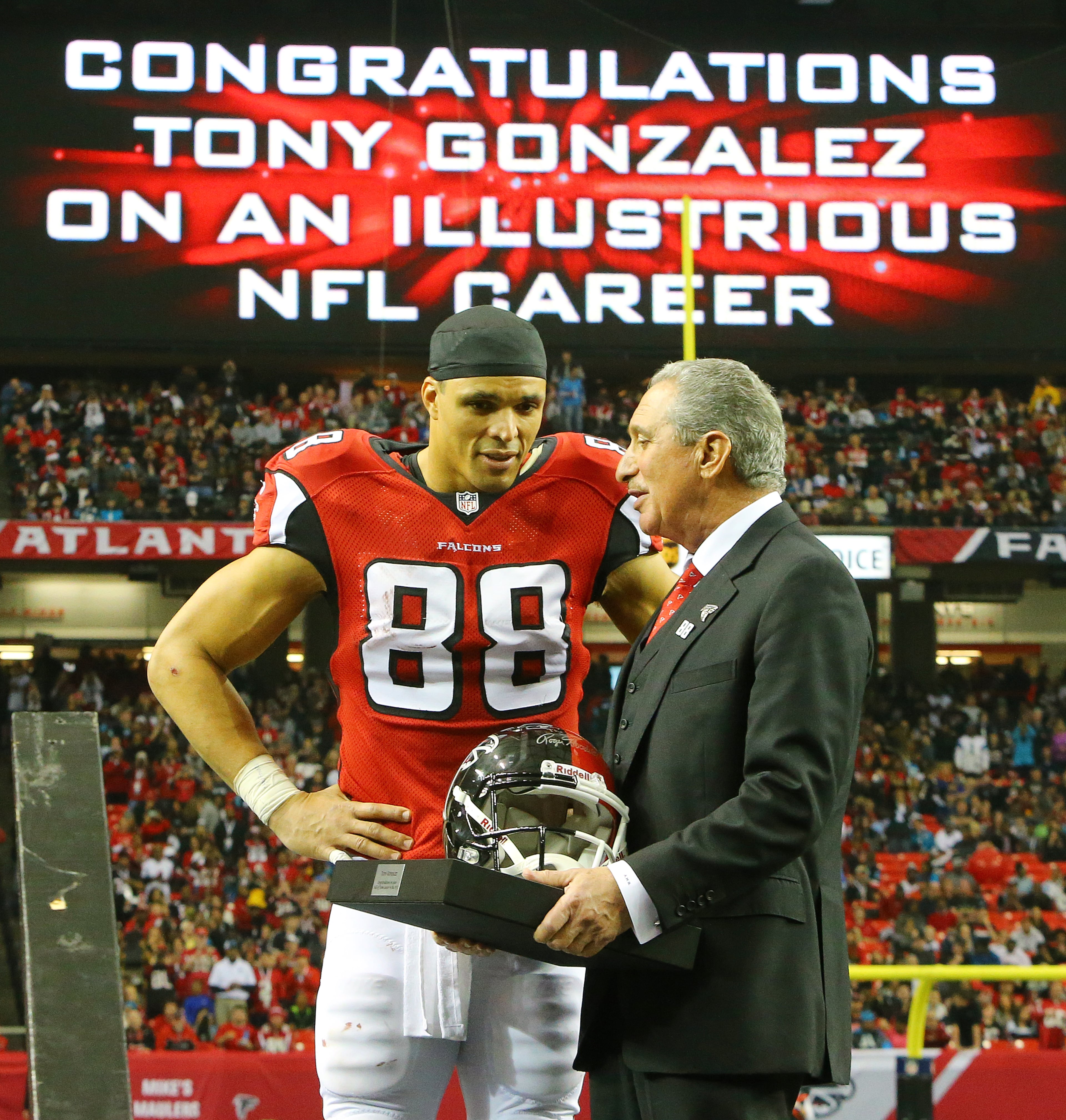 Falcons owner Arthur Blank presents tight end Tony Gonzalez a helmet during a half time ceremony honoring his 17 year NFL football career on Sunday, Dec. 29, 2013, in Atlanta.