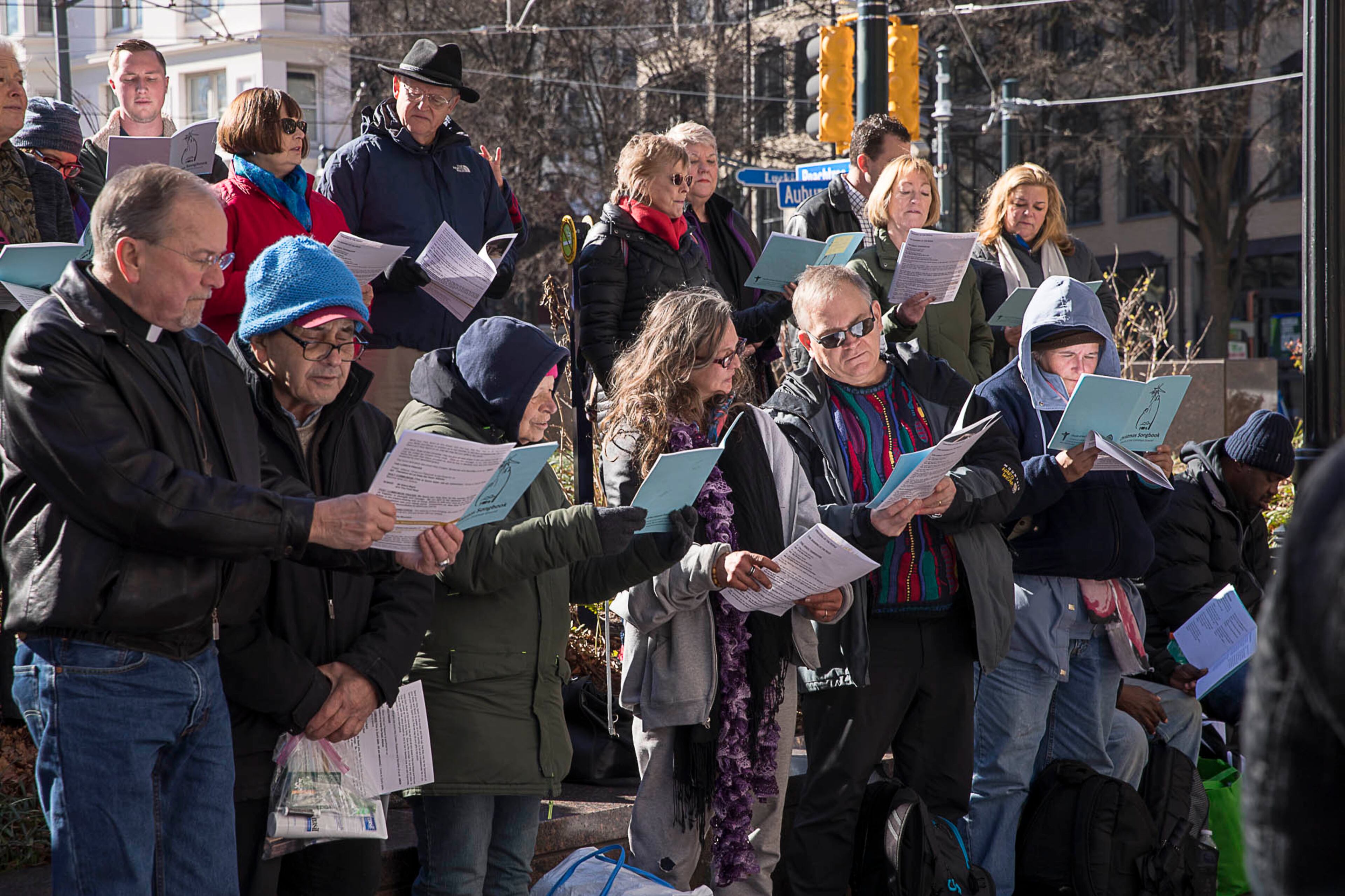12/24/2018 -- Atlanta, Georgia -- Members of the homeless community and members of Saint Phillips Cathedral follow along during a Church of the Common Ground Christmas Eve service for the homeless at Woodruff Park in Atlanta, Monday, December 24, 2018. (ALYSSA POINTER/ALYSSA.POINTER@AJC.COM)