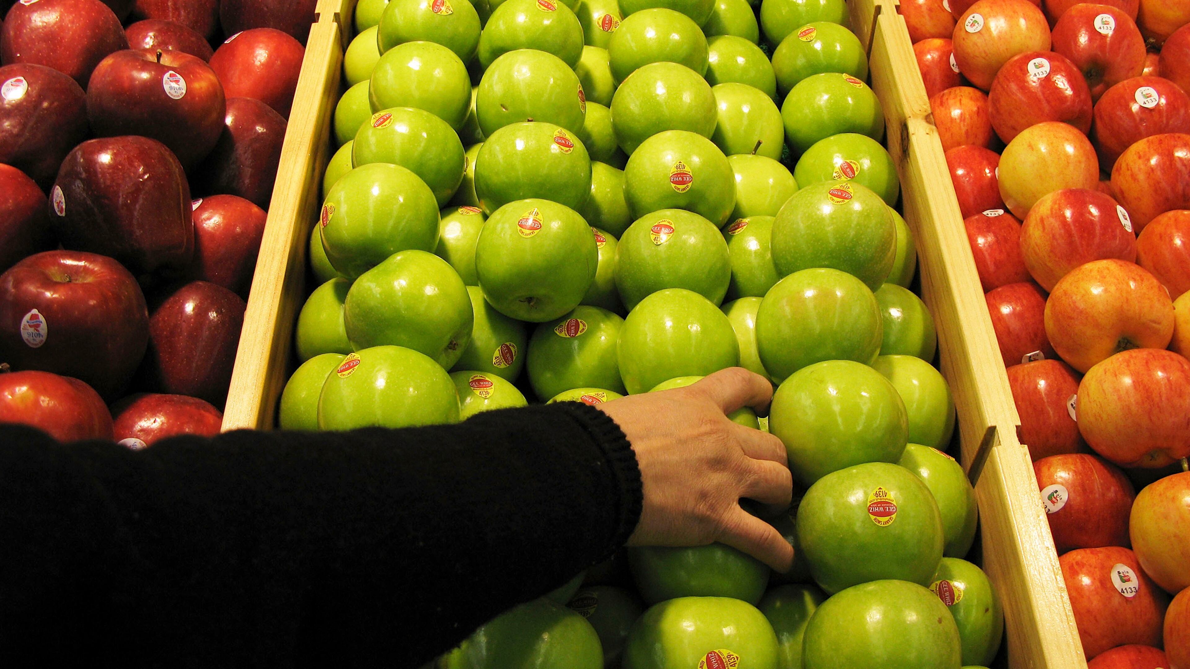 BEIJING - JANUARY 27: A shopper chooses granny smith apples at the newly-opened Tesco supermarket on January 27, 2007 in Beijing, China. The UK giant opened its first own-brand supermarket in Beijing after investing in 46 stores across China under the name of its Chinese partner, Le Gou, which translates as "Happy Shopping". Tesco's new store in Beijing is competing with other international chains that are well established in China, such as Wal-Mart and Carrefour. (Photo by Andrew Wong/Getty Images)