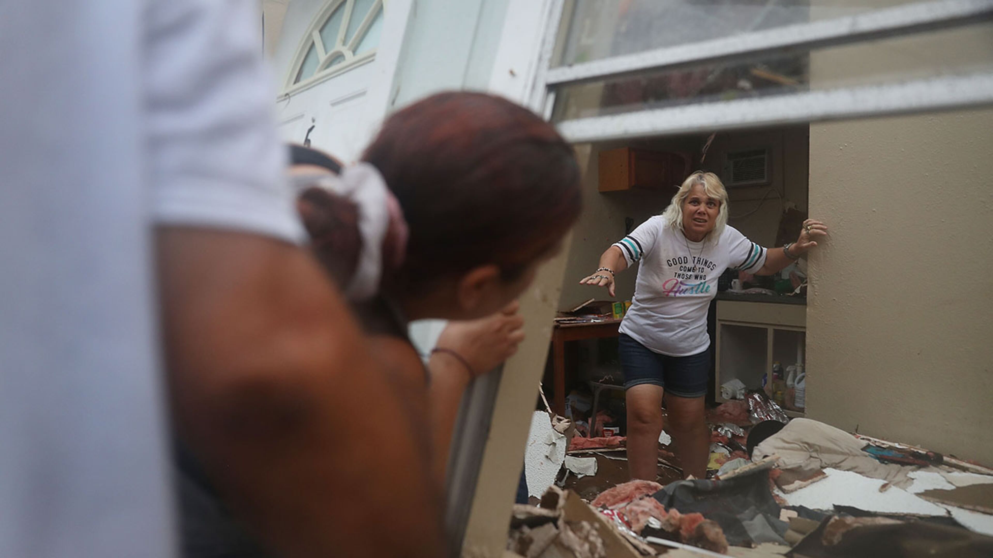 ROCKPORT, TX - AUGUST 26: Donna Raney makes her way out of the wreckage of her home as Daisy Graham tells her she will help her out of the window after Hurricane Harvey destroyed the apartment on August 26, 2017 in Rockport, Texas. Donna was hiding in the shower after the roof blew off and the walls of her home caved in by the winds of Hurricane Harvey. Harvey made landfall shortly after 11 p.m. Friday, just north of Port Aransas as a Category 4 storm and is being reported as the strongest hurricane to hit the United States since Wilma in 2005. Forecasts call for as much as 30 inches of rain to fall by next Wednesday. (Photo by Joe Raedle/Getty Images)