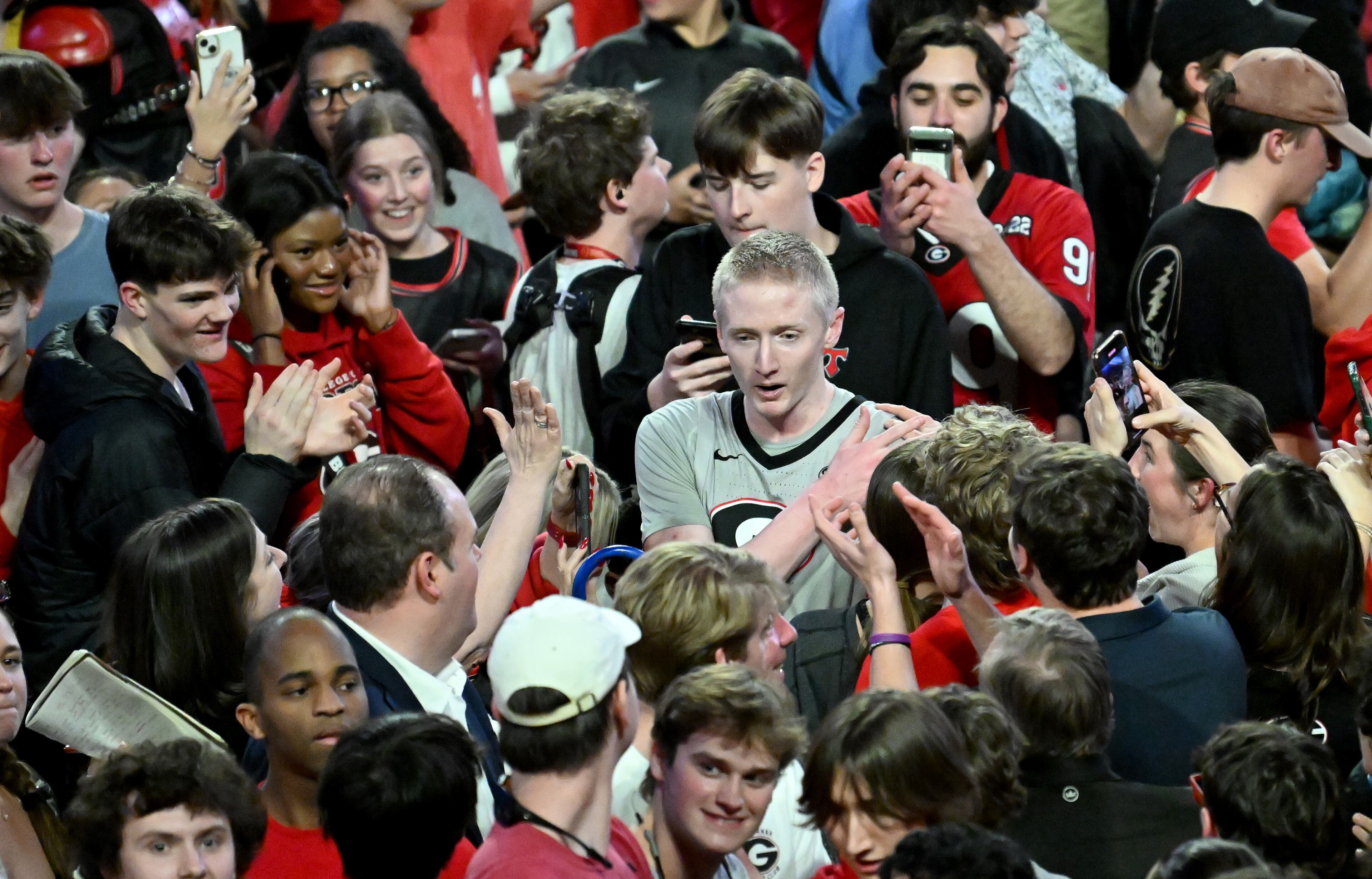 Georgia guard Blue Cain is surrounded by fans after Georgia beat Florida during an NCAA college basketball game at Stegeman Coliseum, Tuesday, February 25, 2025, in Athens. Georgia’s electric home crowd stormed Stegeman Coliseum at the final buzzer of a 88-83 upset of No. 3 Florida Tuesday night. (Hyosub Shin / AJC)