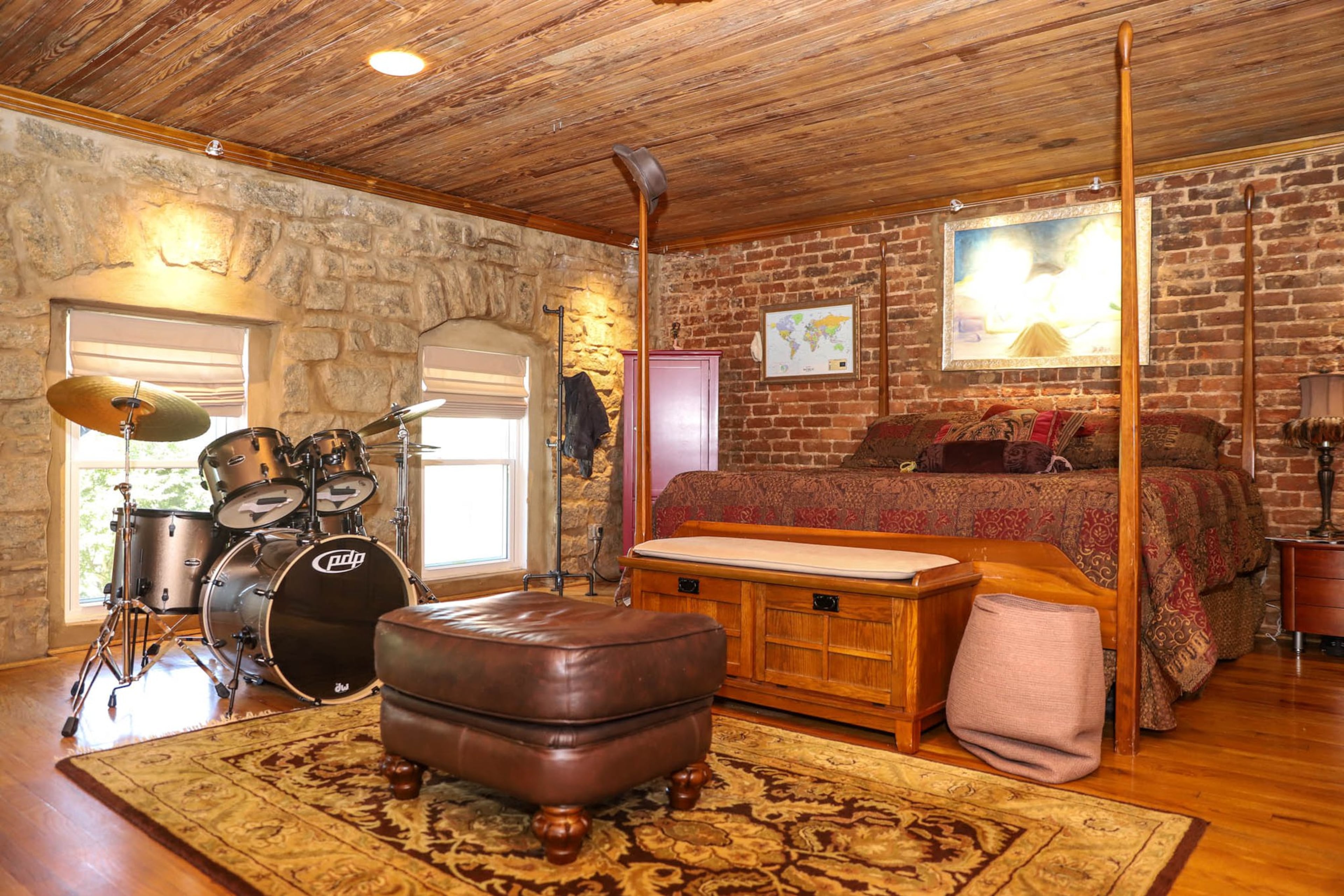 The exposed brick and stone is one of Kevin and Diana Sheldon’s favorite design elements of their Atlanta loft. When they decided to downsize in 2017, the stone features of their loft are one of the things that drew them to it. Their master bedroom shows this feature to a lovely effect. Their bedroom also demonstrates the couple’s interests, with Kevin’s drum set up and a painting by Diana on display above the bed. Text by Shannon Dominy. Photo by Reynolds Rogers.