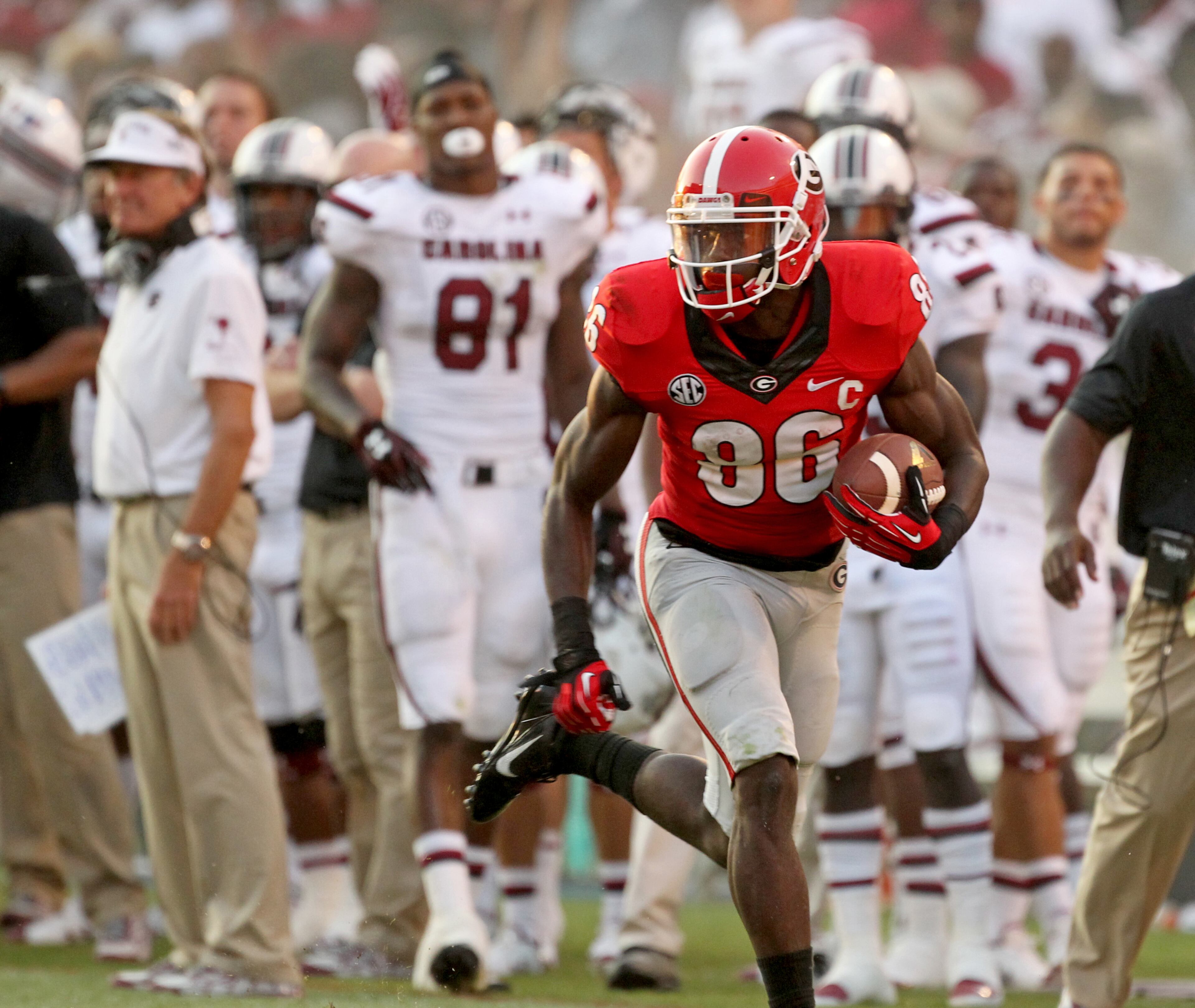 With Spurrier in the background (left), Georgia wide receiver Justin Scott-Wesley (86) runs down the South Carolina sideline on his way for an 85-yard touchdown. JASON GETZ / JGETZ@AJC.COM