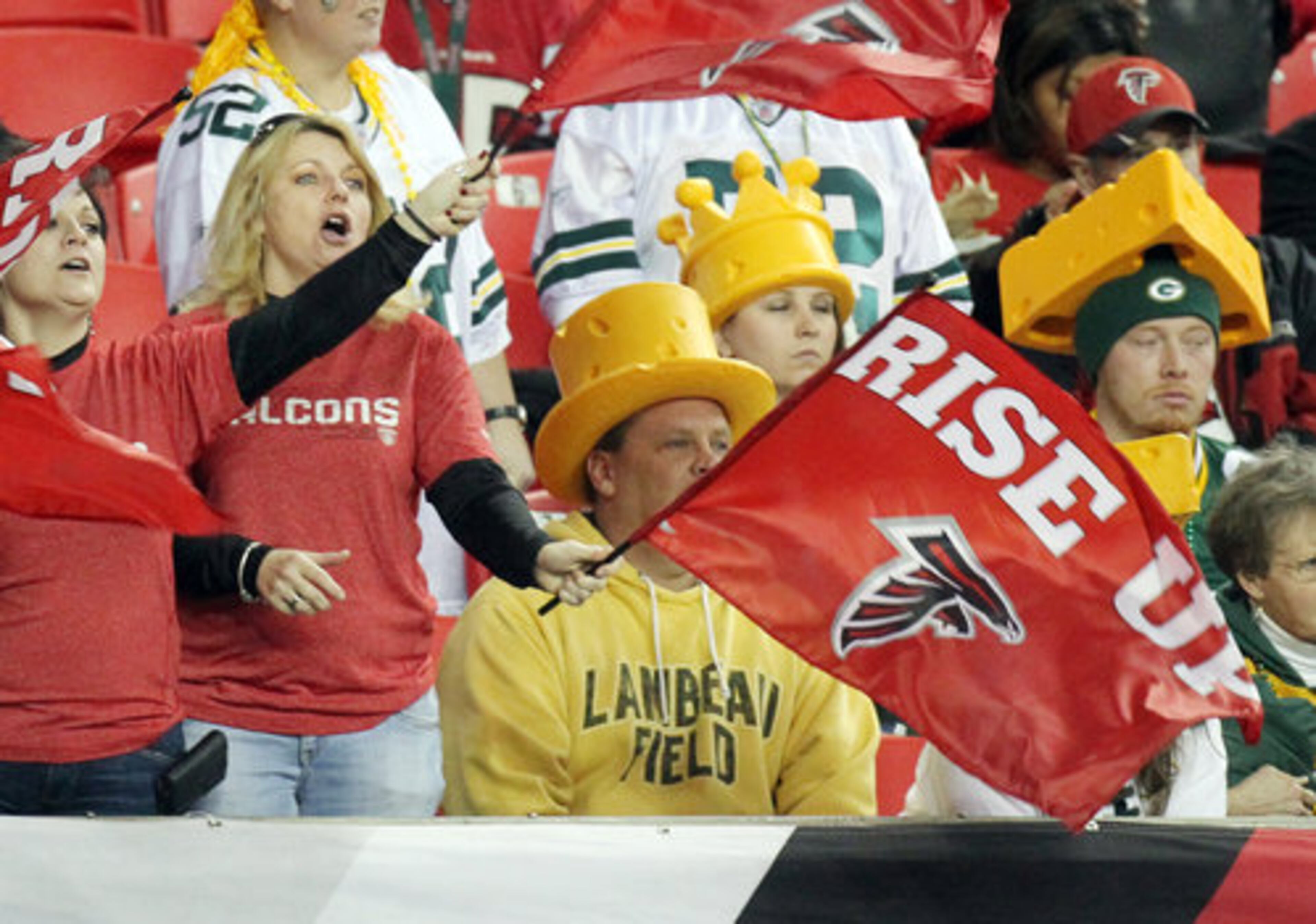 Falcons fans wave Rise Up flags given out to the first fans arriving for the NFC divisional playoff game as the Falcons take the field to warm up with Green Bay fans wearing cheese heads looking on at the Georgia Dome.
