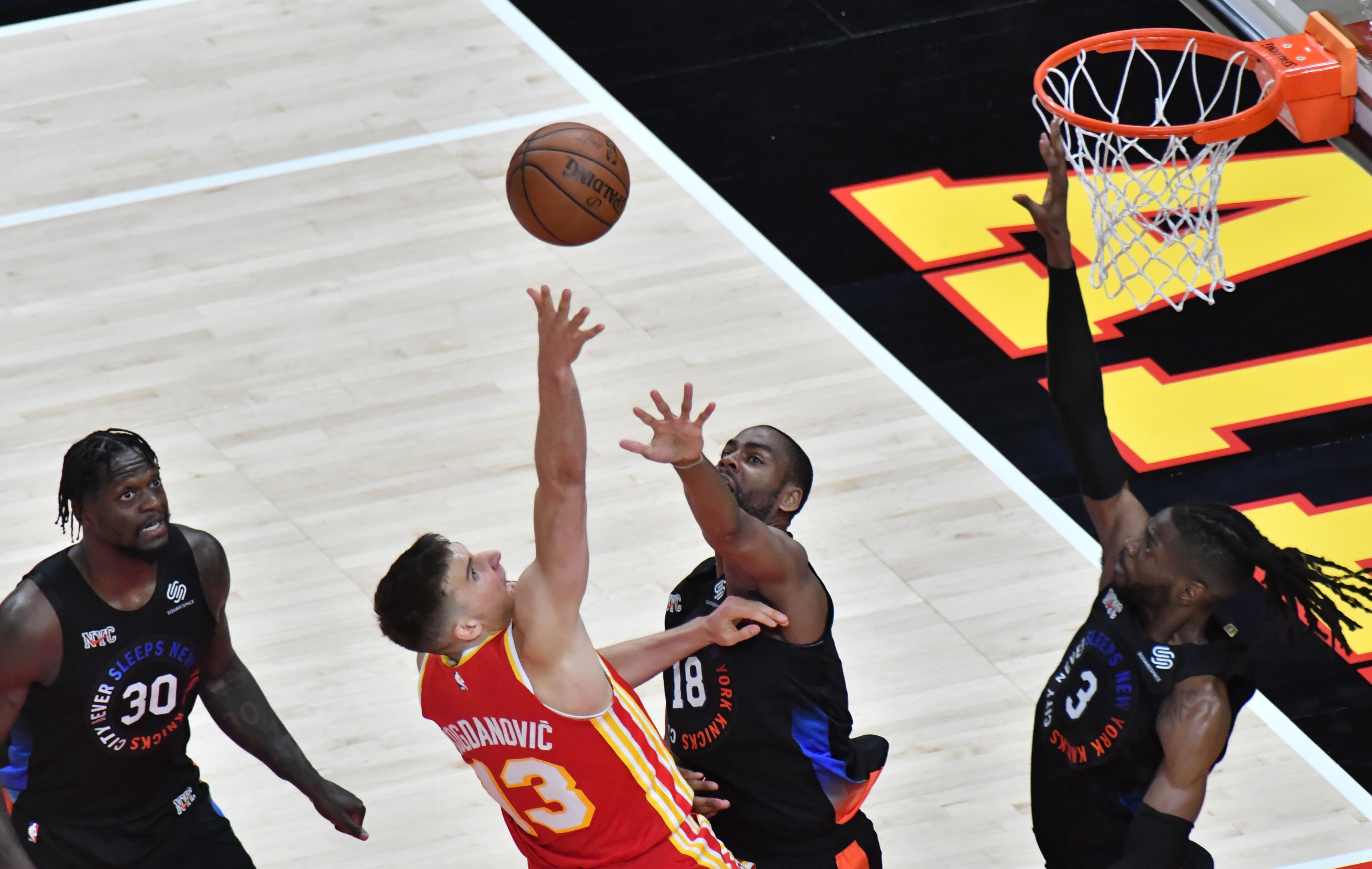 Hawks guard Bogdan Bogdanovic (13) shoots over New York Knicks guard Alec Burks (18) and center Nerlens Noel (3). (Hyosub Shin / Hyosub.Shin@ajc.com)