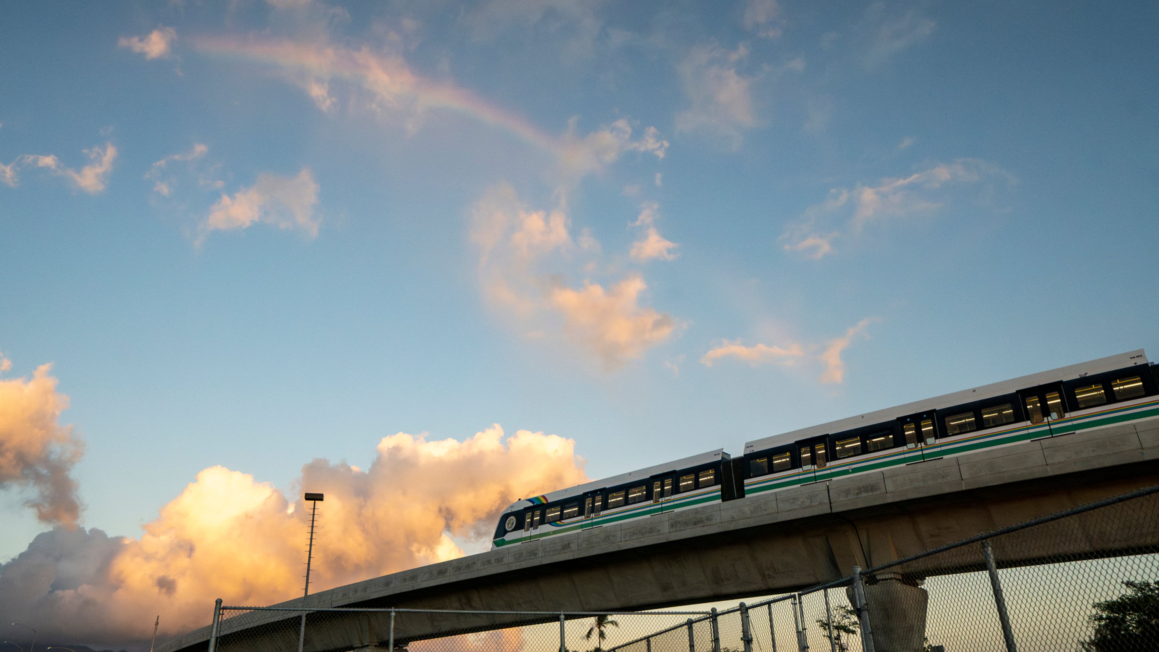 FILE - A rainbow arches over a Honolulu Skyline train at sunset, Sept. 19, 2024, in Honolulu. (AP Photo/Mengshin Lin, File)