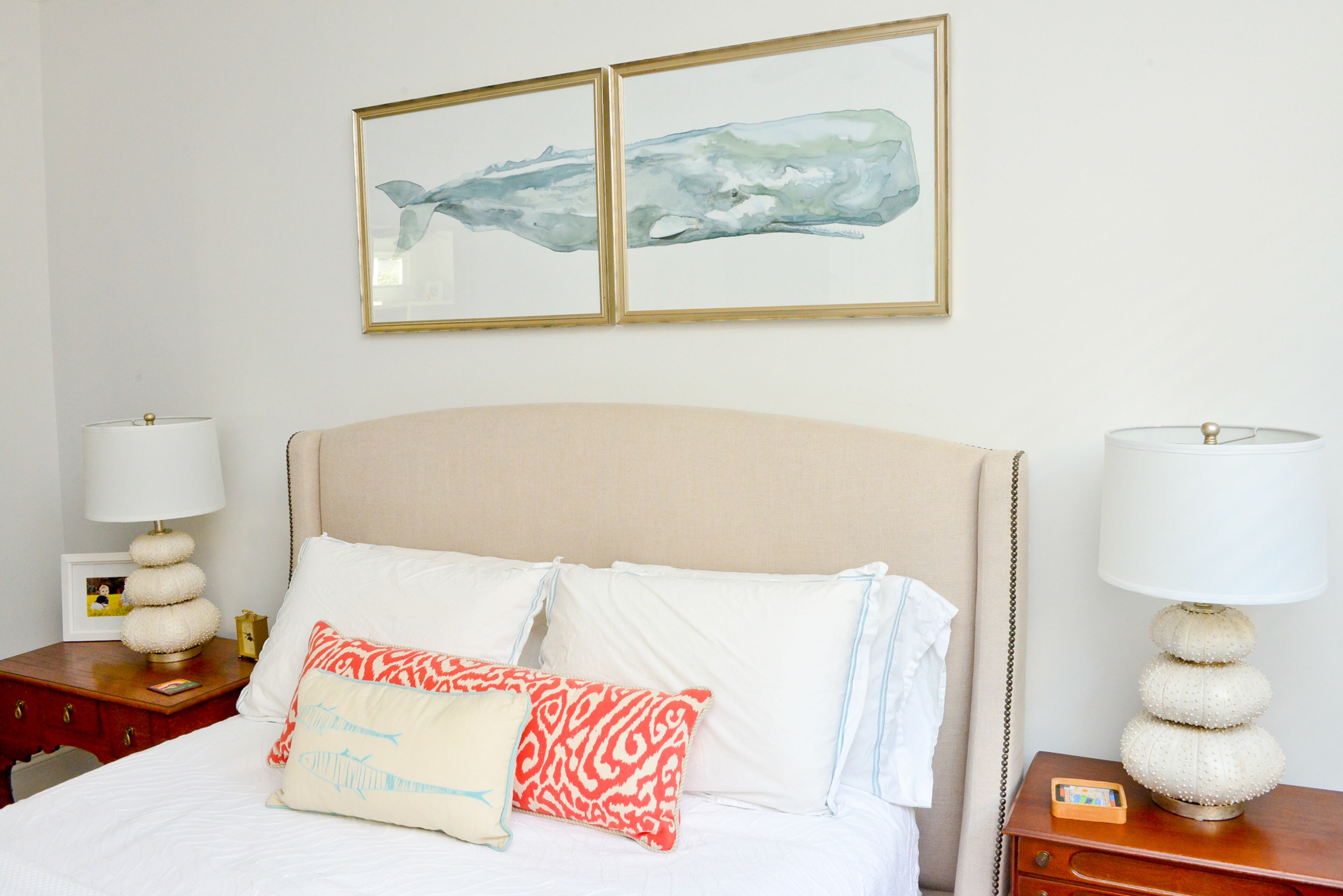 In the guest bedroom, the homeowner maintains a subtle maritime decor. Gold-framed art of a giant whale, from Ballard Backroom in Atlanta, appears to float on a sea of white walls above the bed, while a white throw pillow features the pale aqua outline of more sea creatures.