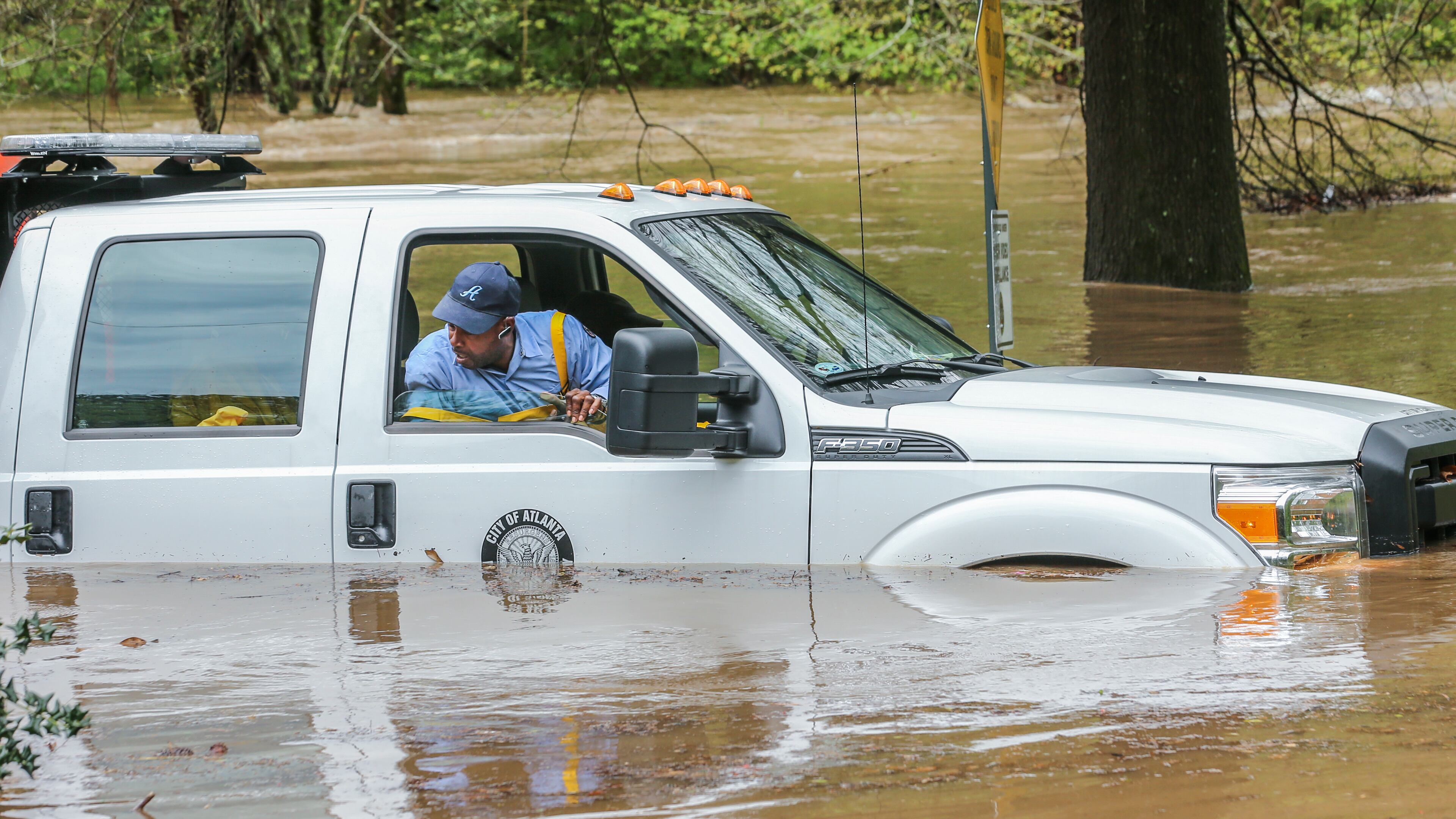 An Atlanta Public Works crew got caught in the Peachtree Creek overflow onto the flooded Woodward Way as they were delivering Road Block equipment and had to be rescued by the Atlanta Fire Rescue's Swift Water Dive Team. JOHN SPINK /JSPINK@AJC.COM