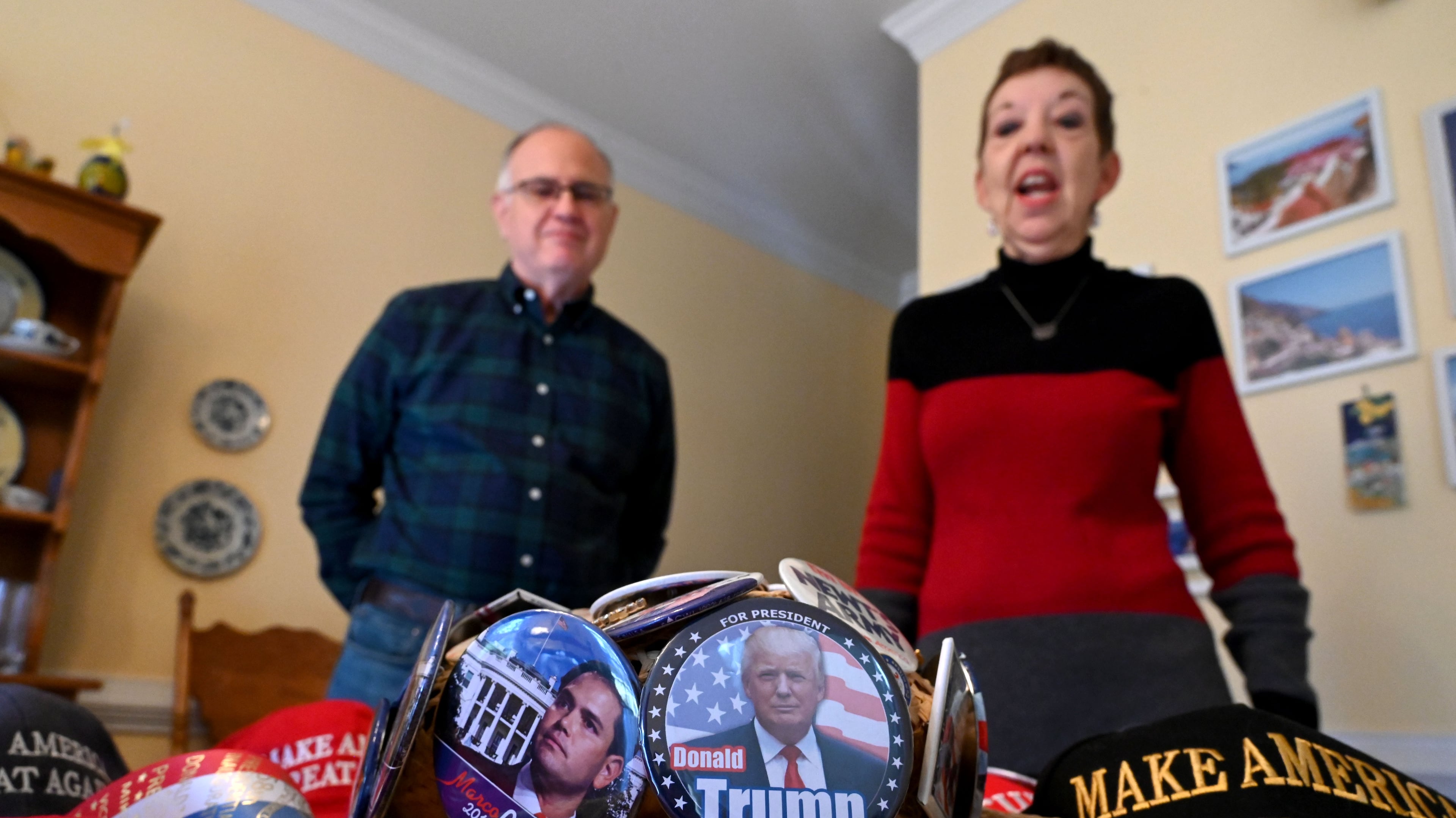 Judy Griffin shows her cowboy hat decorated with Republican buttons she has collected over the years as her husband Brian Griffin (left) looks on at their home in Woodstock on Tuesday, January 14, 2025. Judy and Brian Griffin are traveling to Washington D.C. for Donald Trump's second inauguration. (Hyosub Shin / AJC)