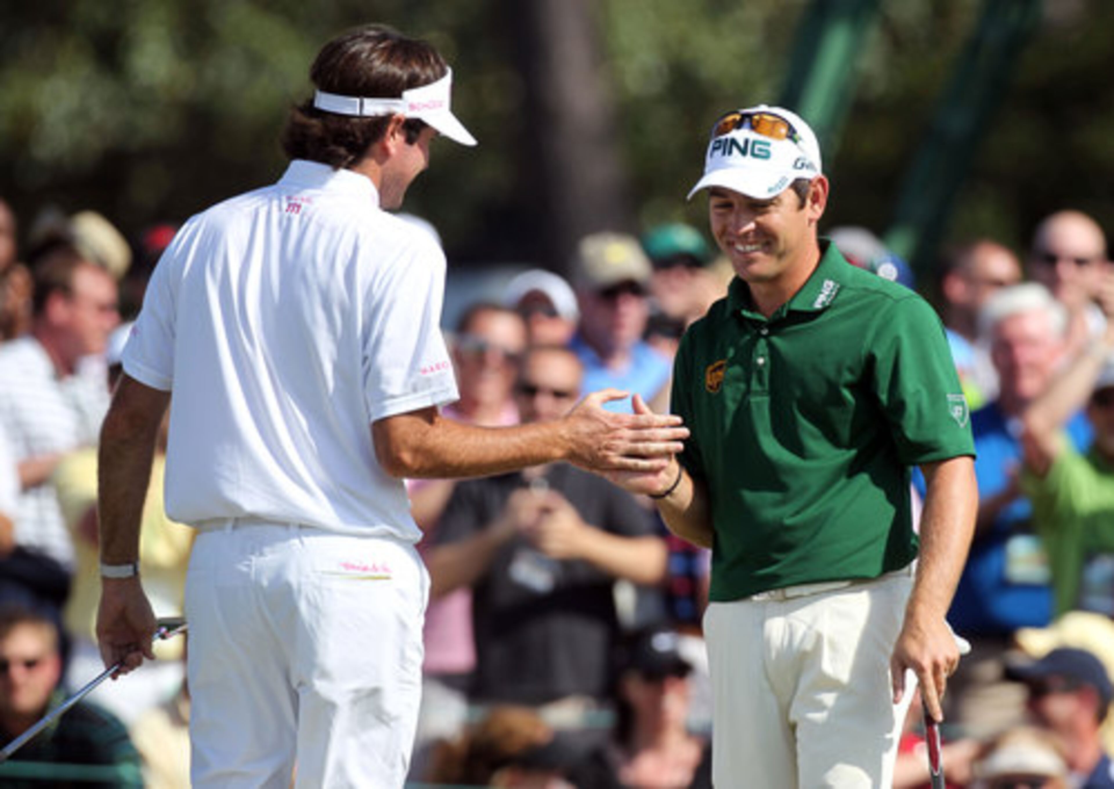 Bubba Watson (left) gets five from Louis Oosthuizen after Watson just missed a birdie putt. He saved par to remain 7-under.Oosthuizen also made par on the hole to stay 9-under during Sunday's final round at the Masters.