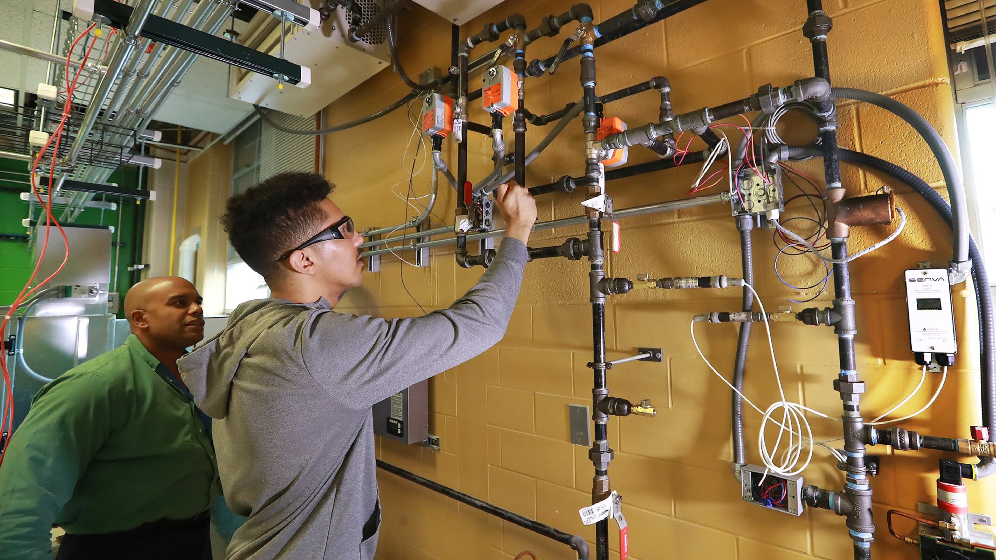 Building automation instructor Robert Croom looks on while student Jomaris Soseph works on a hydronic wall during his class in the Building Automation Systems program at Georgia Piedmont Technical College on Thursday, Jan. 30, 2020, in Clarkston. The college is one of 22 schools in the Technical College System of Georgia, which has received federal grant money to help train workers laid off due to the coronavirus pandemic. CURTIS COMPTON / CCOMPTON@AJC.COM
