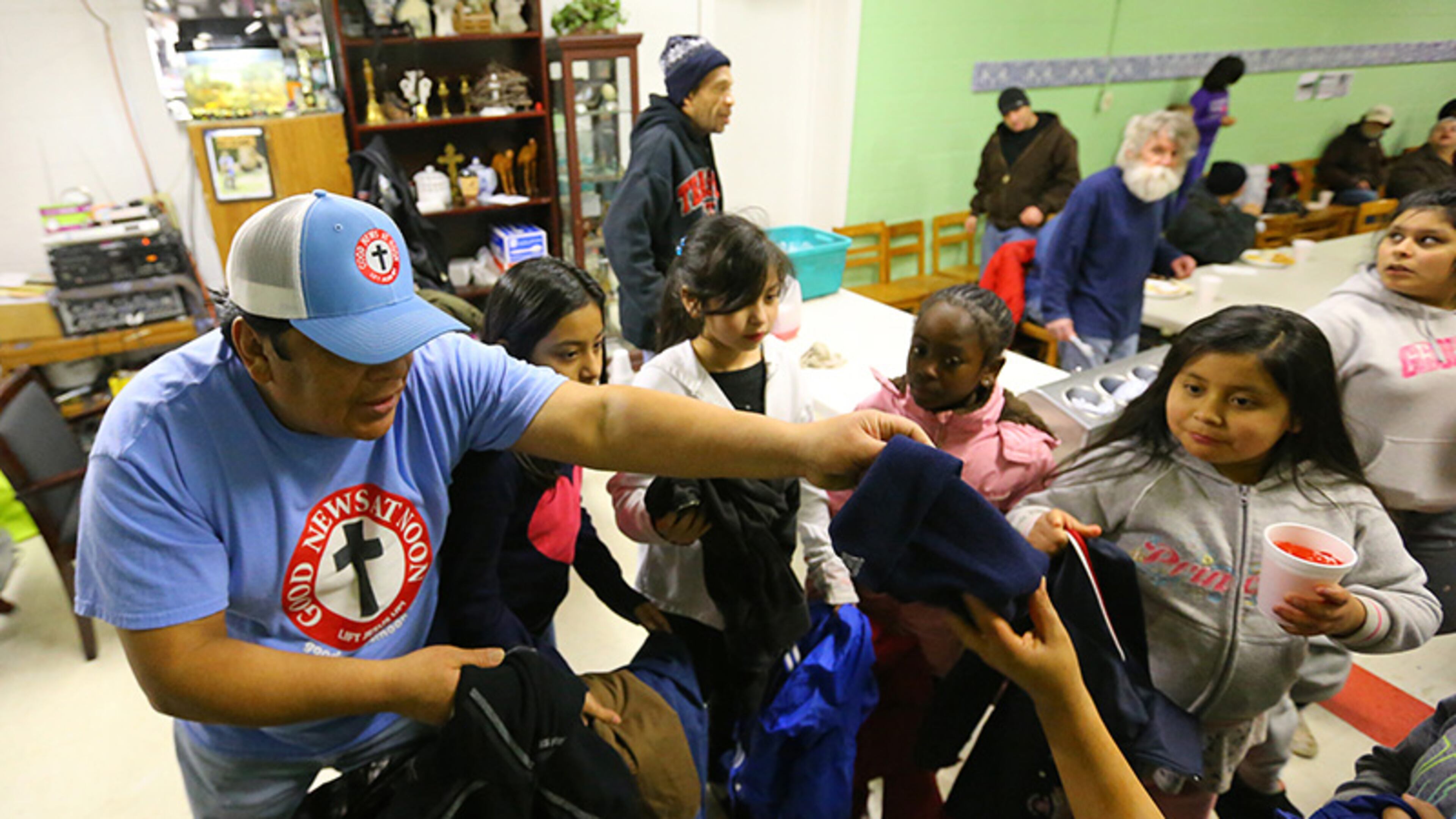 Thomas Ramirez, manager at the Good News At Noon Ministry, hands out donated coats to needy children and the homeless during the winter storm late Wednesday night, Feb. 12, 2014, in Gainesville.
