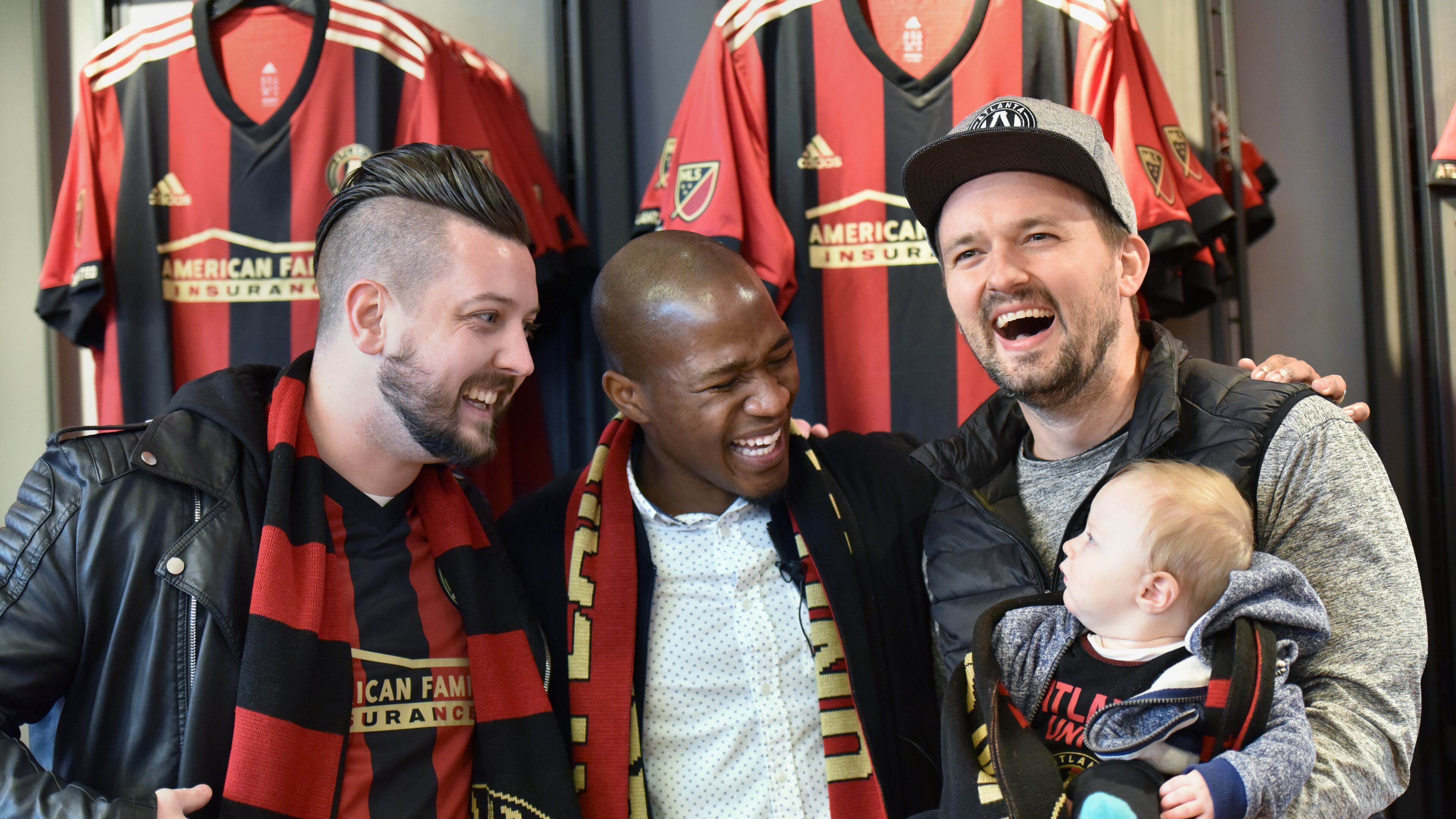 December 15, 2017 Atlanta - New Atlanta United midfielder Darlington Nagbe shares a smile with fans Adam Boyle (left) and Andrew Amerson with his son Elon, 6-months, as they pose for a group photograph at the Team Store at Mercedes-Benz Stadium on Friday, December 15, 2017. Atlanta United introduced midfielder Darlington Nagbe to the media Friday at Mercedes-Benz Stadium. Hyosub Shin / hshin@ajc.com