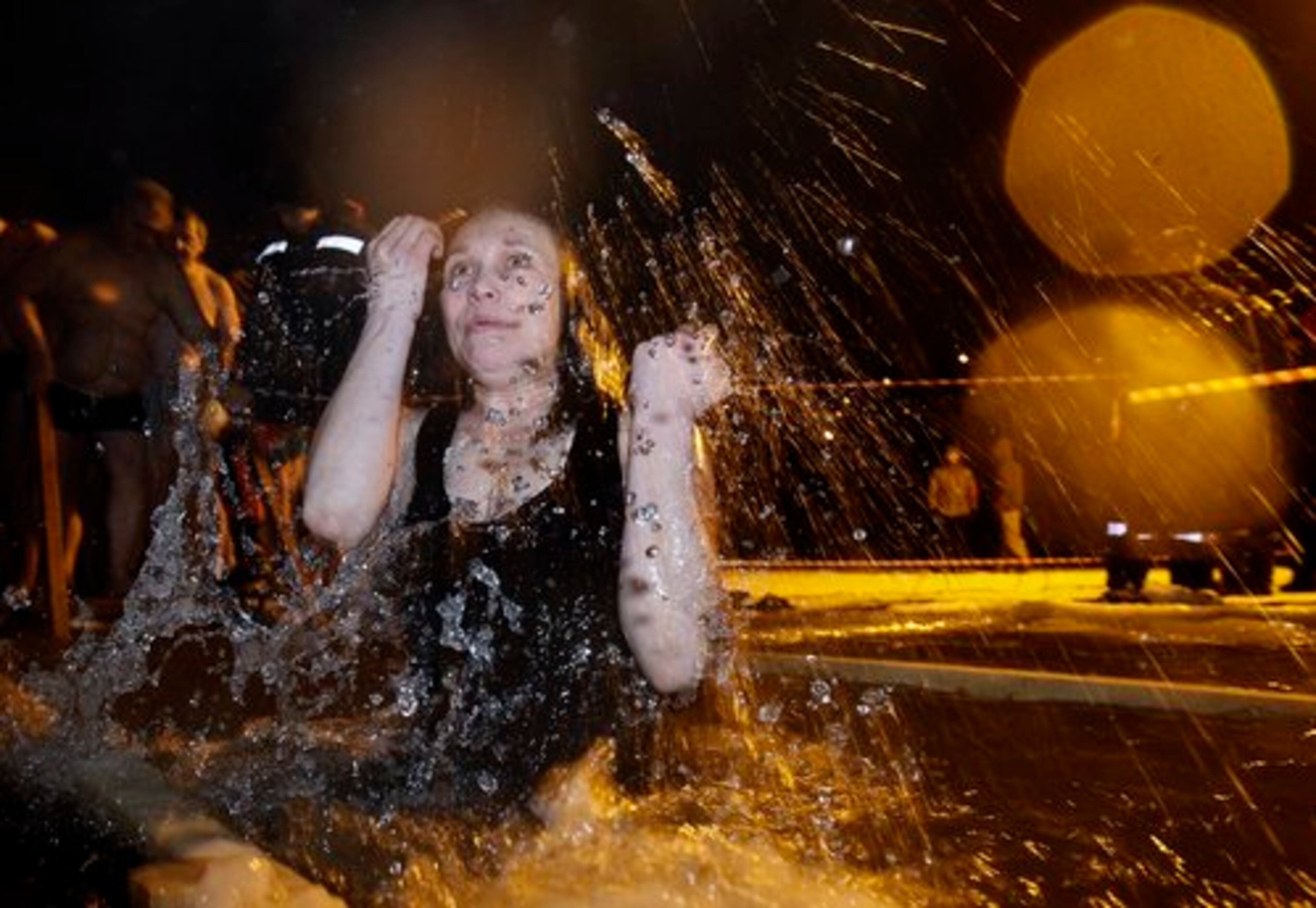 A Russian woman crosses herself as she emerges from an ice hole made in the shape of a cross in a traditional Epiphany celebration in Moscow, Russia, early Wednesday, Jan 19, 2011.