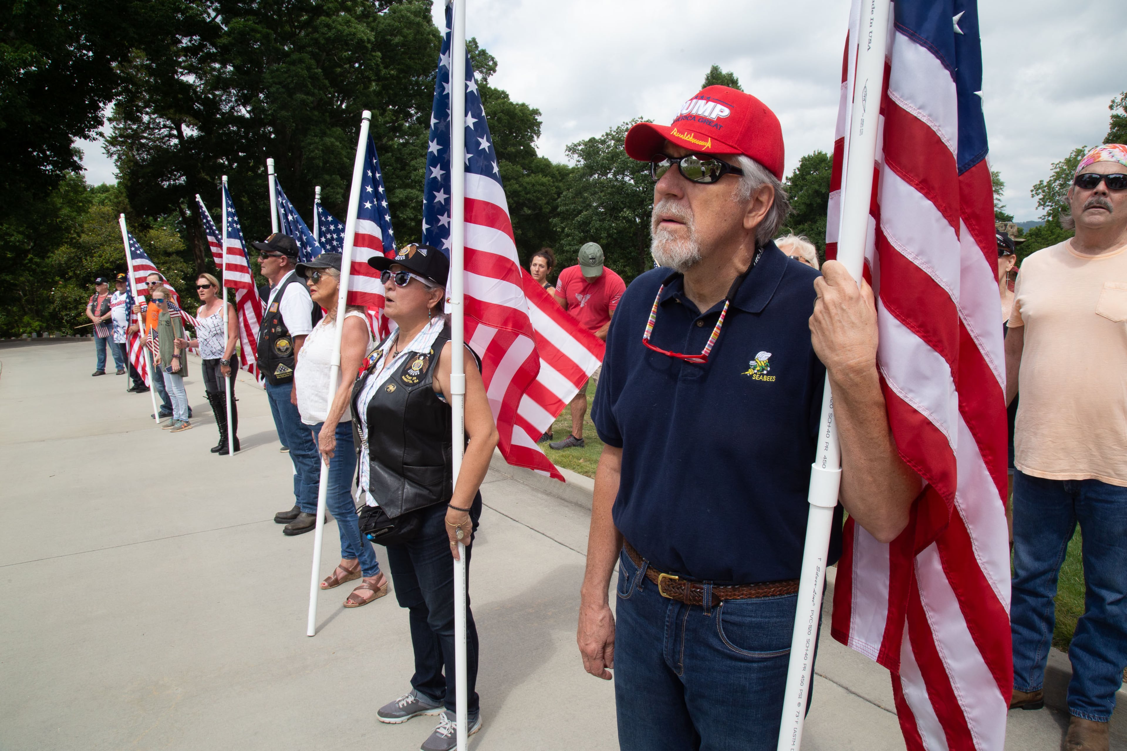 People stand at attention during an unofficial wreath-laying ceremony at the Marietta National Cemetery before the National Guard, Blackhawk flyover on Monday, May 25, 2020