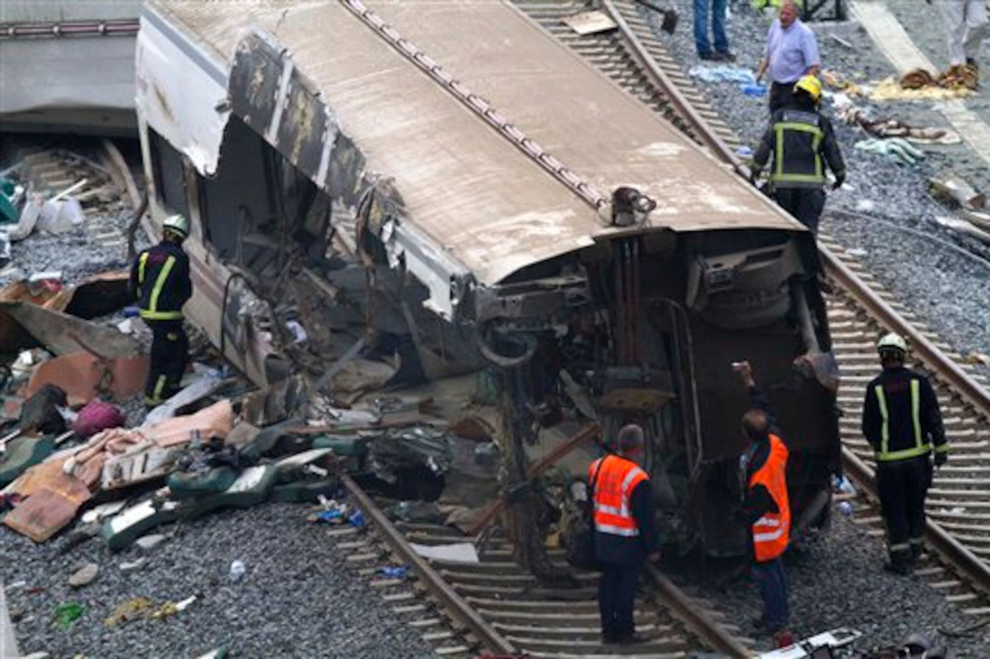 Rail personnel and firefighters inspect derailed cars at the site of a train accident in Santiago de Compostela, Spain, on Thursday, July 25, 2013. The death toll in a passenger train crash in northwestern Spain rose to 77 Thursday after the train jumped the tracks on a curvy stretch of track just before arriving in the northwestern shrine city, a judicial official said Thursday. (AP Photo/ Lalo Villar)