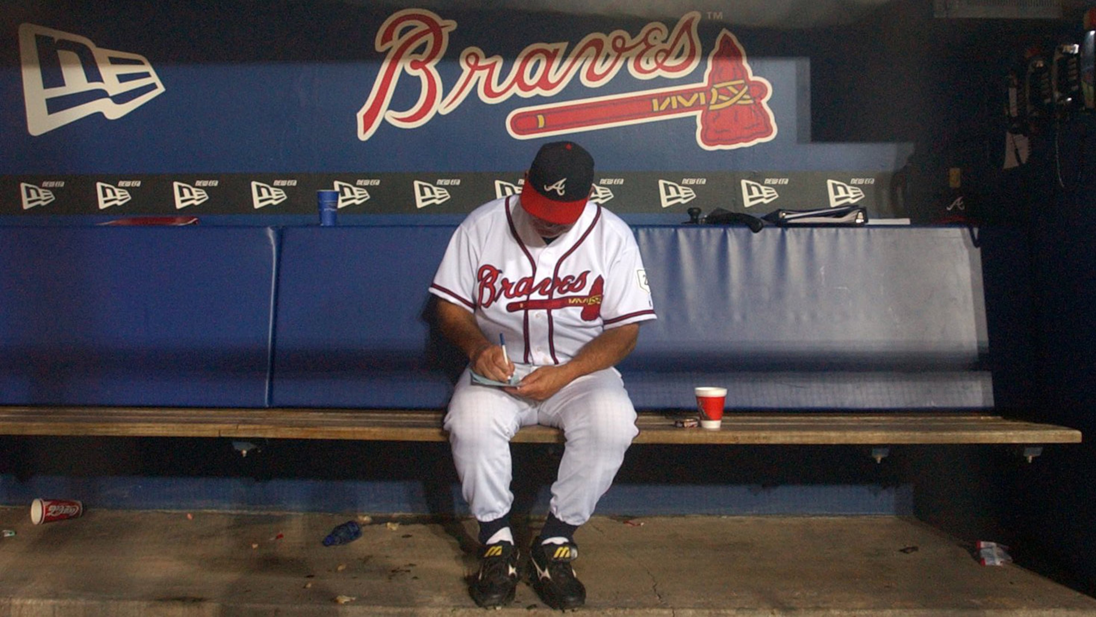 Sitting in an empty dugout, Braves manager Bobby Cox goes over his lineup before the start of a game on Sept. 28, 2004 at Turner Field. (David Tulis/AJC file)