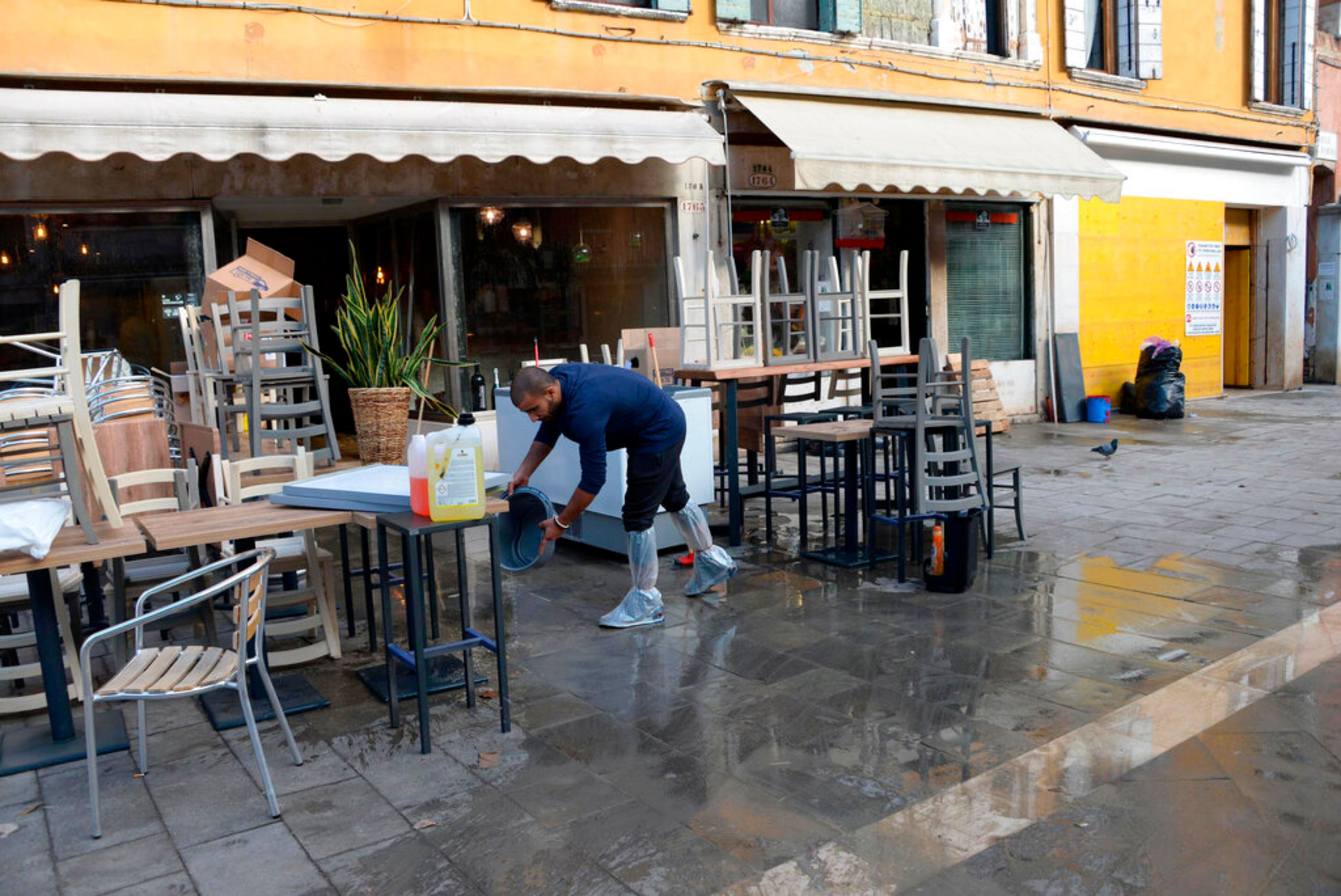 A man cleans up following a flooding in Venice, Italy, Thursday, Nov. 14, 2019. The worst flooding in Venice in more than 50 years has prompted calls to better protect the historic city from rising sea levels as officials calculated hundreds of millions of euros in damage. The water reached 1.87 meters above sea level Tuesday, the second-highest level ever recorded in the city. (Andrea Merola/ANSA via AP)