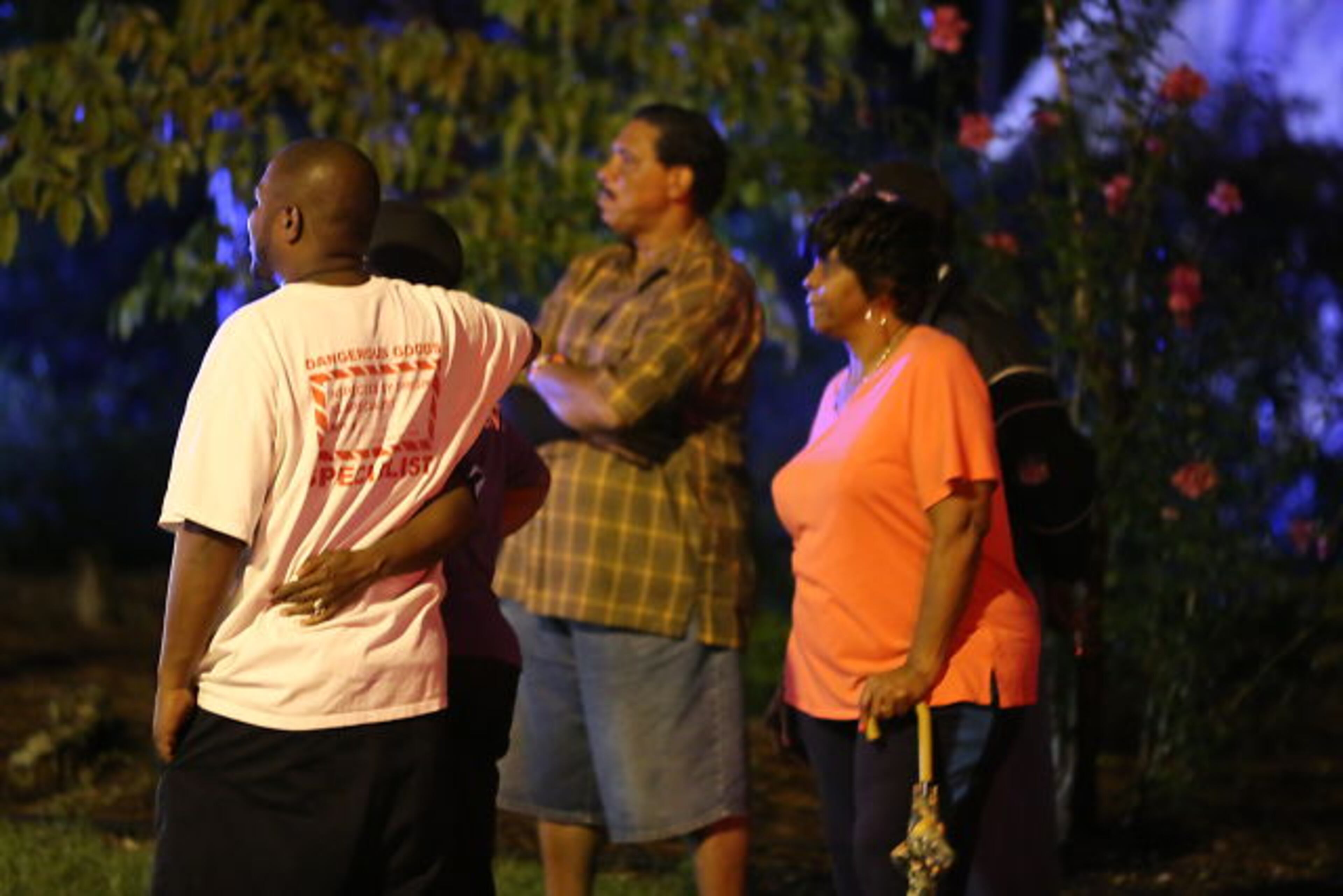 Neighbors gather outside the house on Revere Road in southwest Atlanta where three people died in a fire early Tuesday.